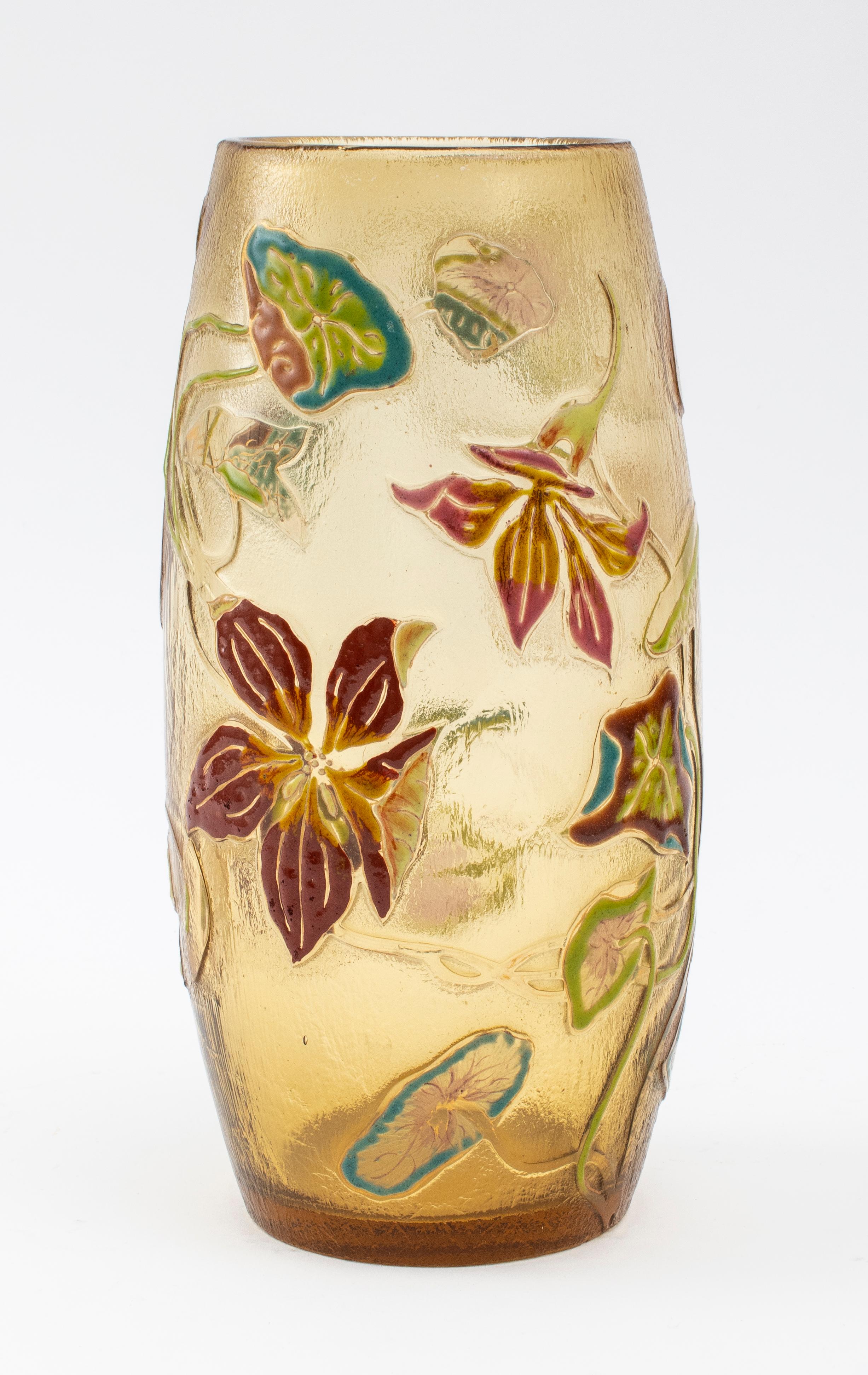 Galle amber enameled art glass vase with floral motif, of ovoid form, and with a textured and polished surface, enameled poppies, irises, and leafy stalks vining around the cylindrical form in green, blue, violet, pink, brown, and gold tones are
