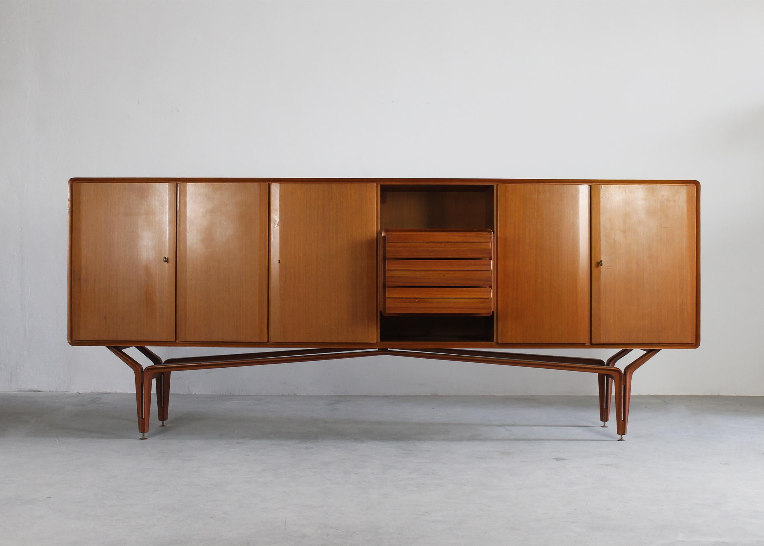 Wooden sideboard with three storage units (two larger and one small) and three frontal drawers with a structure entirely realized in wood and brass details (keys and feet). 
Manufactured by Galleria Mobili d'Arte in Cantù, Italy, during the