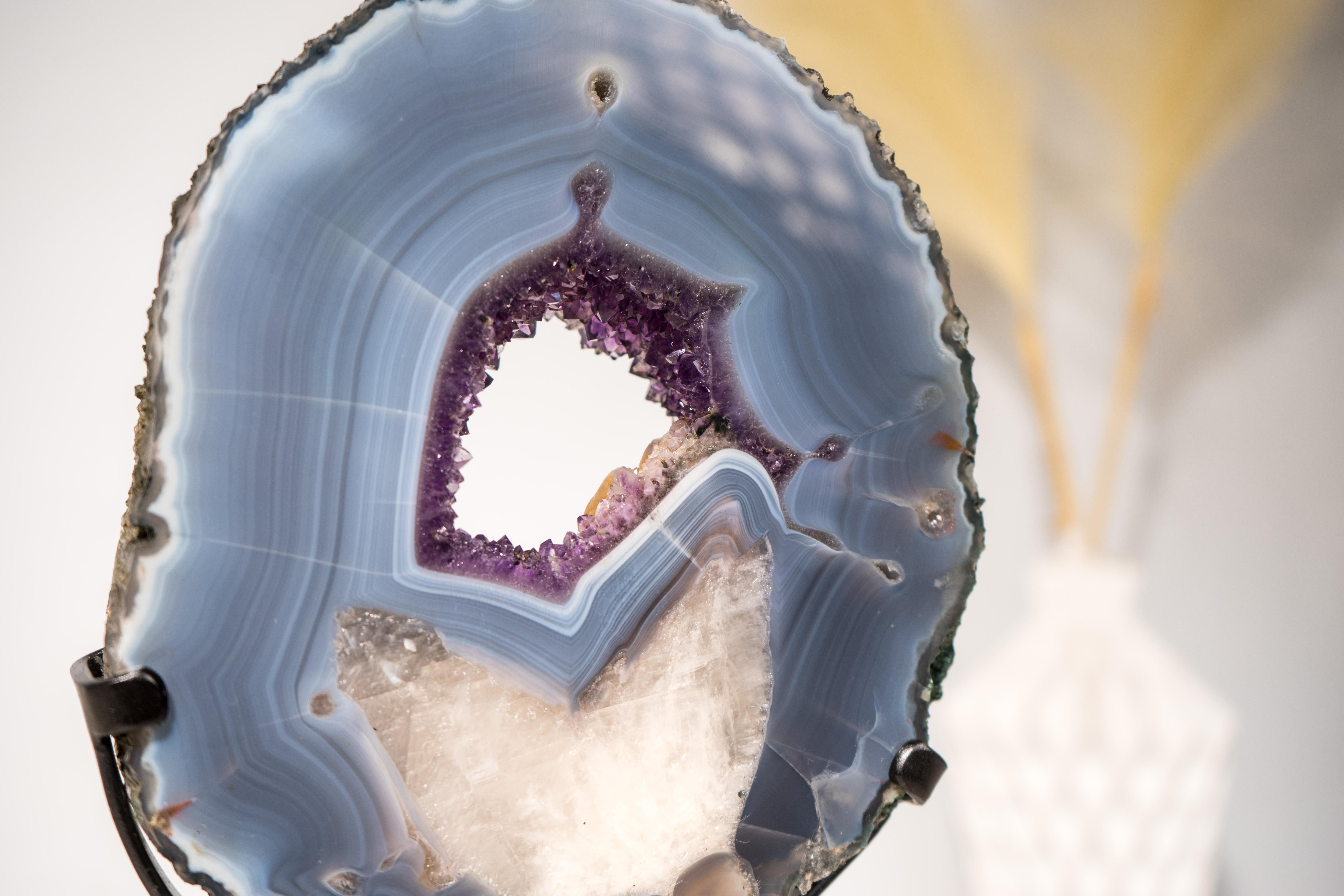 Raro esemplare di agata: Una fetta di geode di agata unica nel suo genere in cui è presente una calcite 

▫️ Descrizione

Questo esemplare da galleria mostra un'interazione naturale tra calcite e agata. Inizialmente, la calcite si formò in una