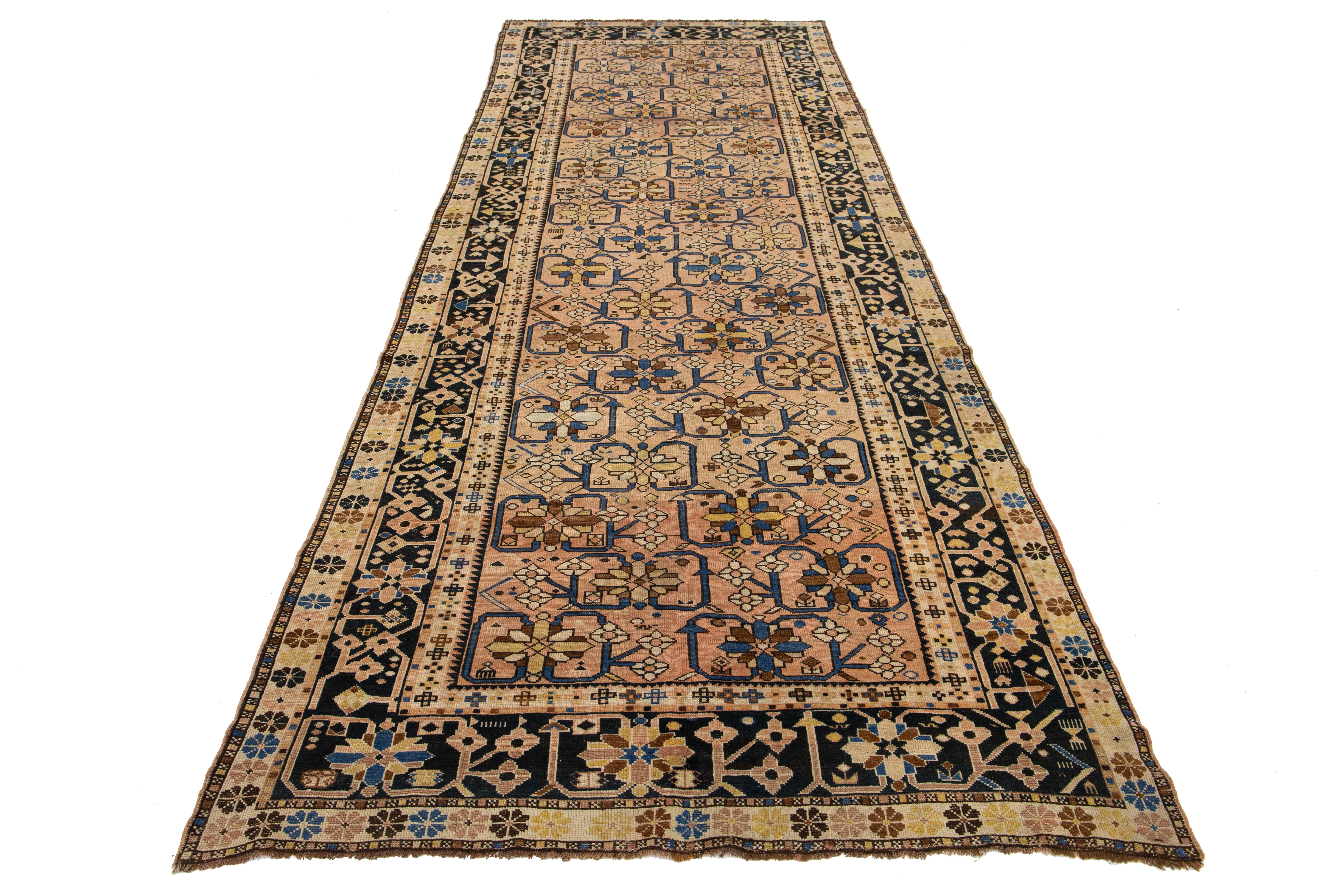 This antique Karabaugh handmade wool rug. Crafted with meticulous attention to detail, this exquisite piece features an all-over design that beautifully blends shades of blue, tan-beige, and brown. The rich peach field textures of the wool add