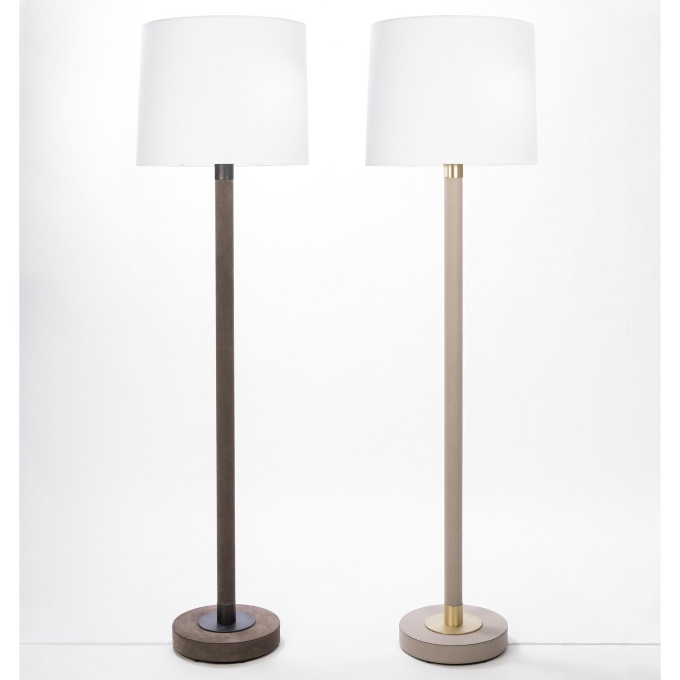 Sophisticated and timeless, this floor lamp will add subtle elegance to a modern interior thanks to its exquisite craftsmanship and delicate color palette. The wooden structure comprises a round base and a stem upholstered in leather with