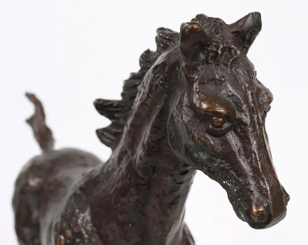 Our patinated bronze figure of a galloping horse is mounted on a reddish-brown stained plinth and is apparently unsigned.  Finely sculpted in clay and cast in bronze likely in the mid to late 20th century.  In very good condition.  A few scuffs and