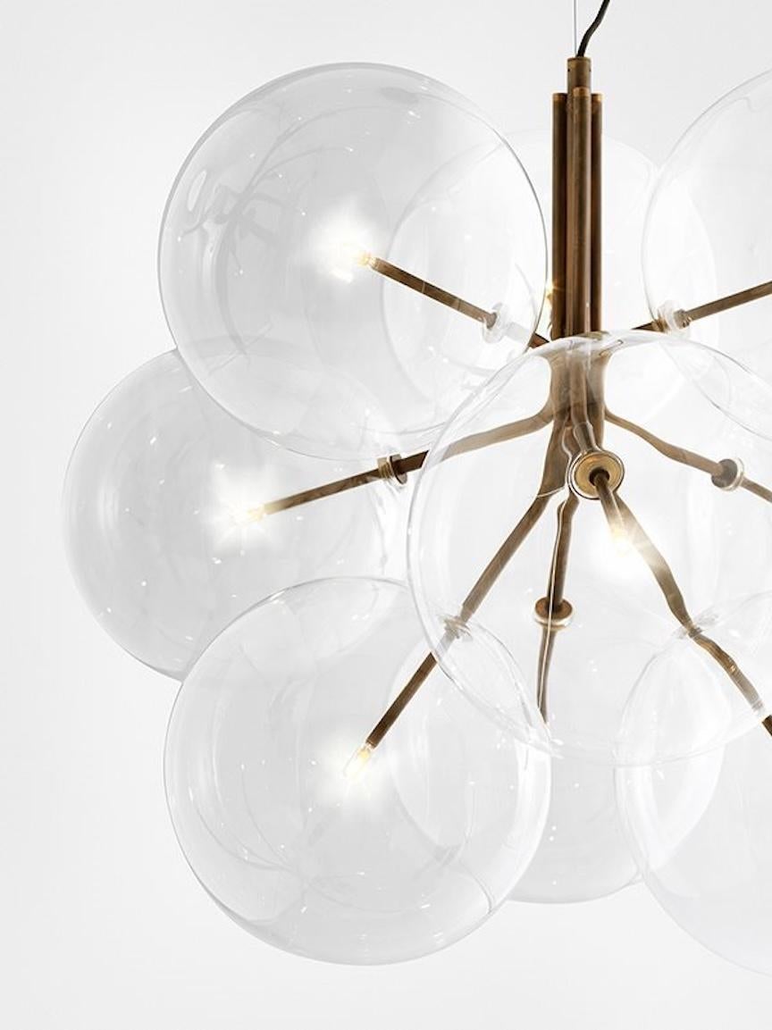 La Lámpara de suspensión Bolle Cielo es una lámpara colgante con luz LED regulable que presenta una estructura de latón bruñido a mano con 6 esferas de vidrio soplado transparente. La lámpara tiene bombillas LED e incluye cables eléctricos y de