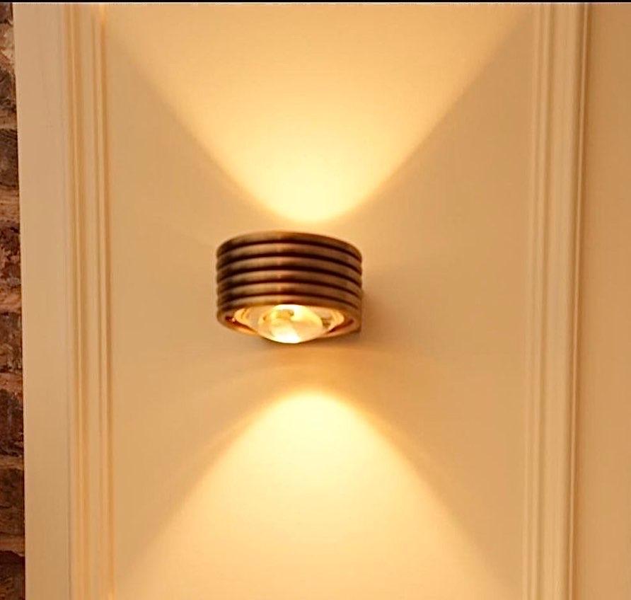 Aplique Art Decó GALUPA, una obra maestra del diseño que combina sin esfuerzo elegancia y funcionalidad. Este impresionante aplique de pared está elaborado en el atemporal estilo Art Déco, con un cuerpo cilíndrico de líneas rayadas que desprende
