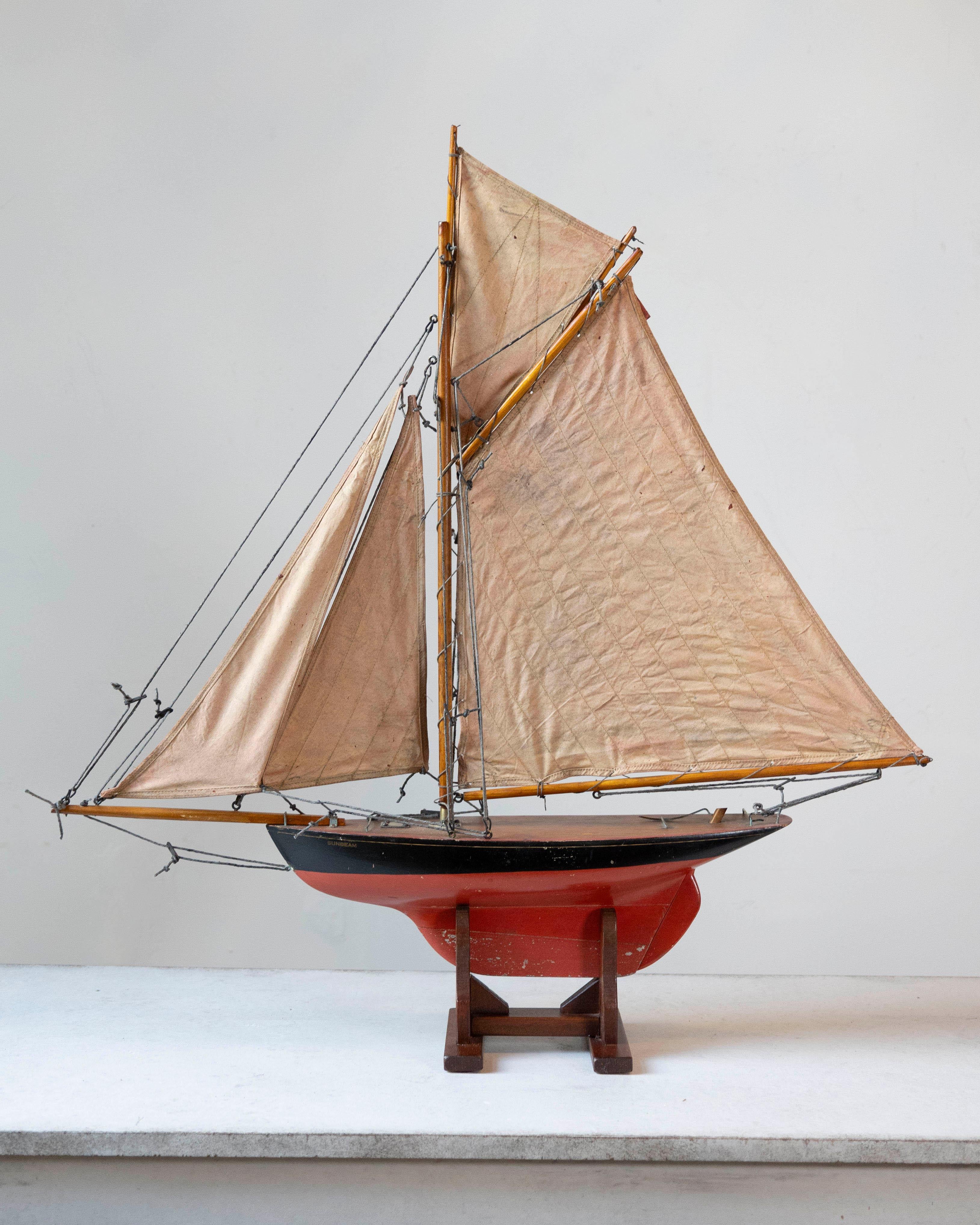 Un precioso yate de estanque de principios del siglo XX, atribuido al famoso minorista londinense Gamage's. Este modelo de cúter con aparejo de garfio presenta un casco rojo finamente pintado con una sección superior pintada de negro y se asienta