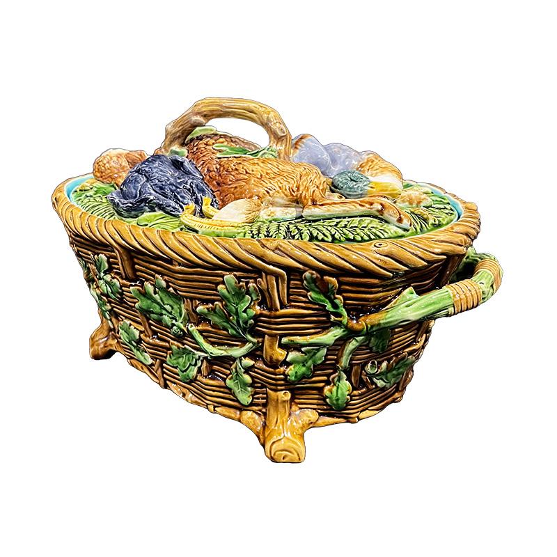 Majolica oval game terrine, featuring a palette of green, blue, brown, and ochre. Adorned with a woven basket encircled by an oak leaf garland, the lid showcases a prominent relief depicting a hunting trophy composed of game birds (hare, mallard