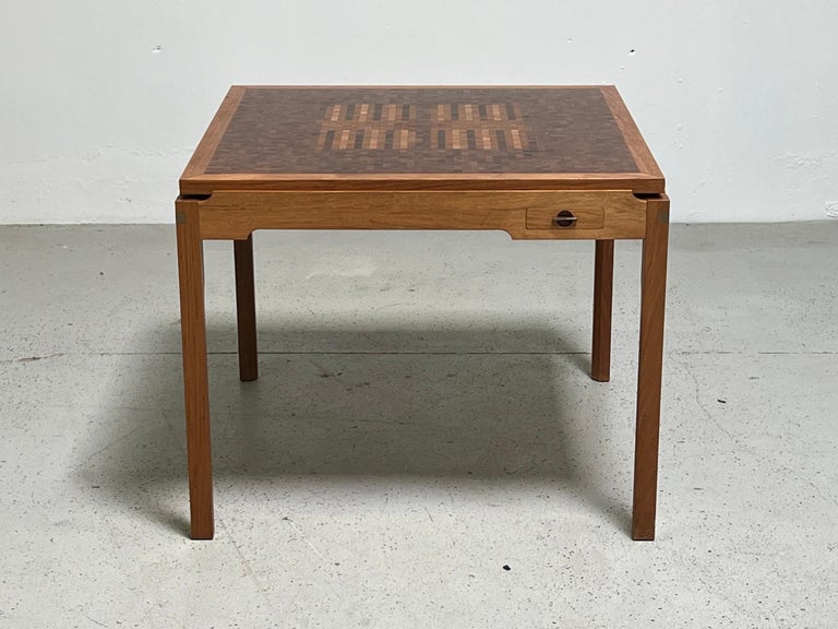 A beautifully crafted game table with drawers and a top with leather on one side and intricately inlayed parquetry backgammon on the other. Brass joinery to each corner.