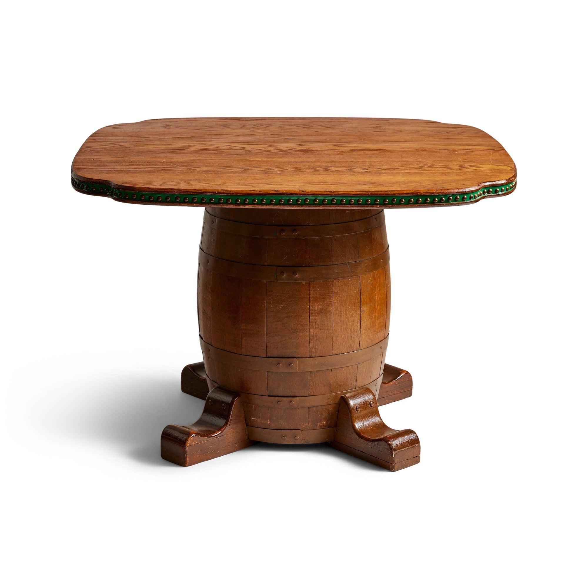 A vintage staved wood and iron barrel game table set with four green nauga upholstered side chairs.