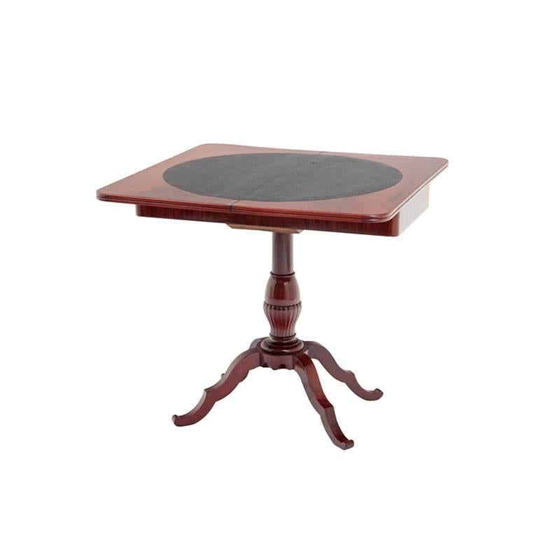 This game table stands on four wavy feet which stem from a central fluted shaft. The top of the table opens to reveal a surface fit for playing games. The playing surface is circular and covered in black leather. 

Table when opened 86 x 86 cm.