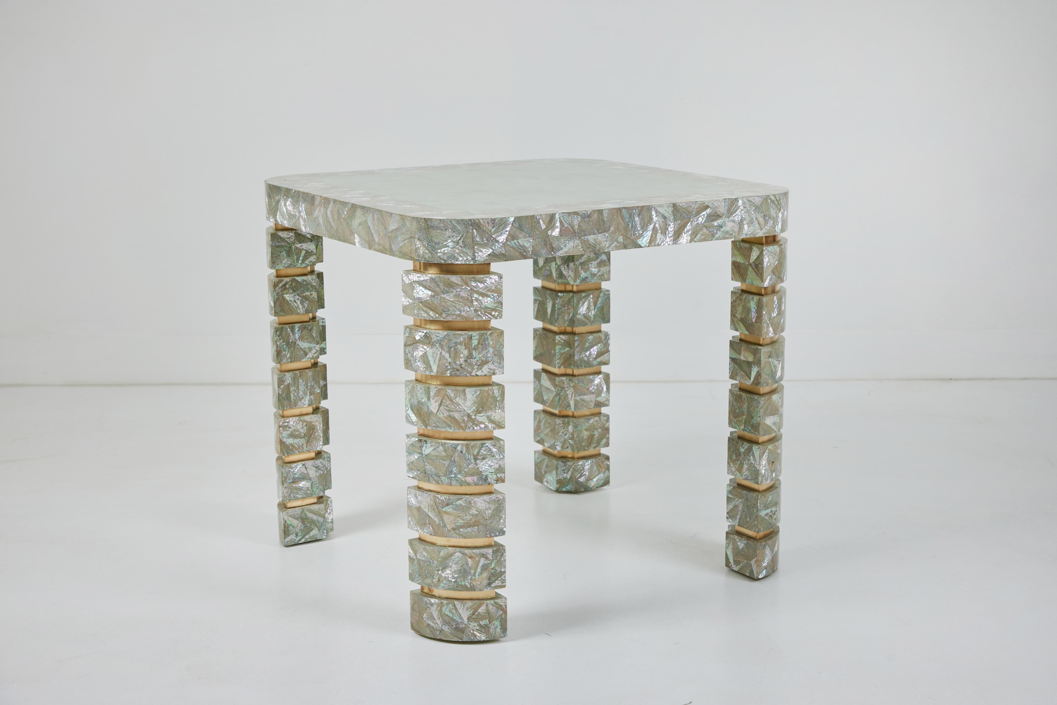 This is a stunning table great as a game table or small dining table most likely designed and made by Maitland Smith. Smith's style is reflected in the use of tessellated natural materials. The table top features tessellated stone surrounded by