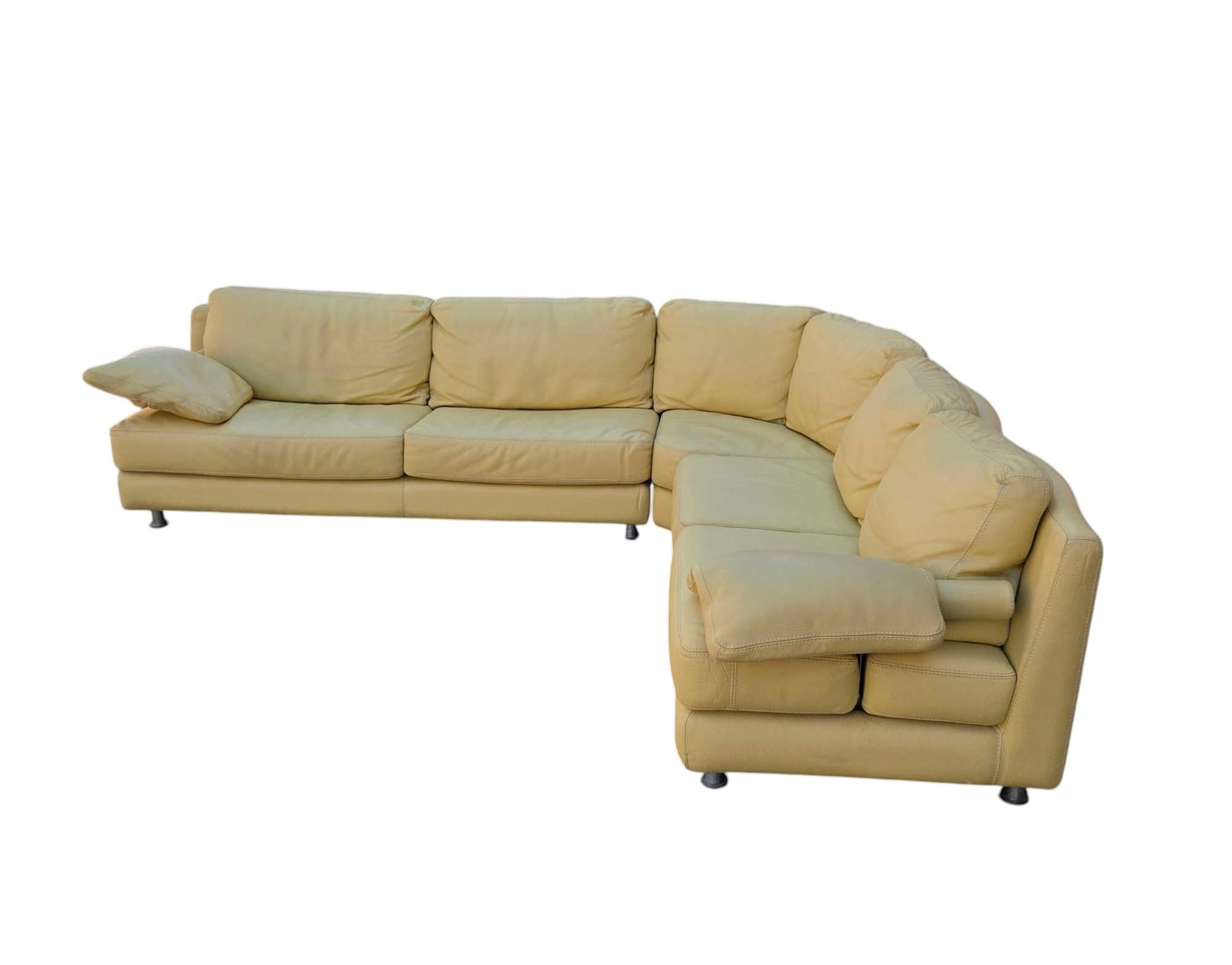 Beautiful quality sofa by Gamma Arredamenti. In high grade muted butter leather. Sofa is three sections raised on brushed steel legs. Two pillows on each end. Leather is in great condition with very little wear.  Beautiful scalloped back makes this