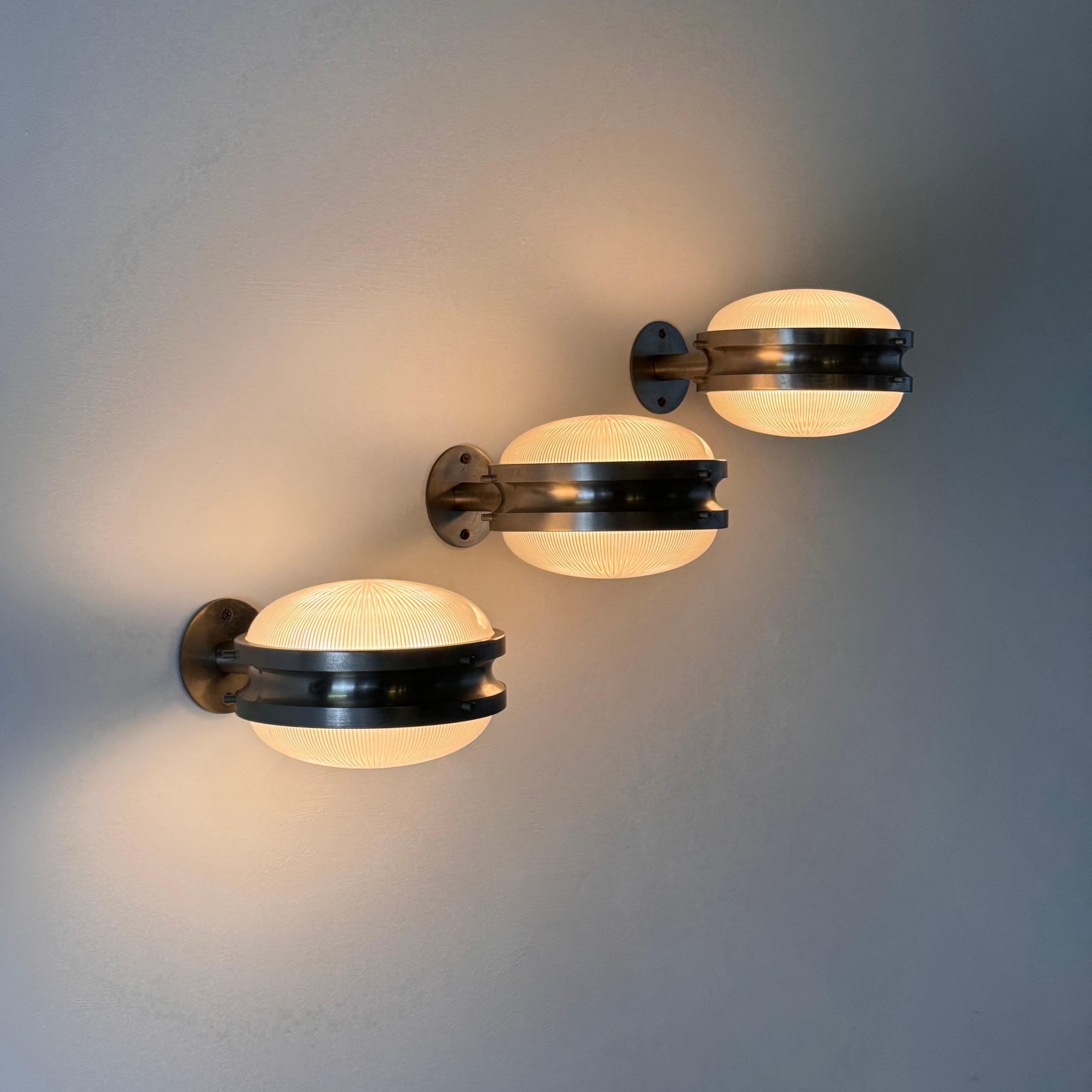A sophisticated trio of wall sconces from the iconic “Gamma” series, designed by Sergio Mazza for Artemide in the 1960s. These pieces epitomize the understated elegance of mid-century Italian design.

Each sconce features a structure in brushed