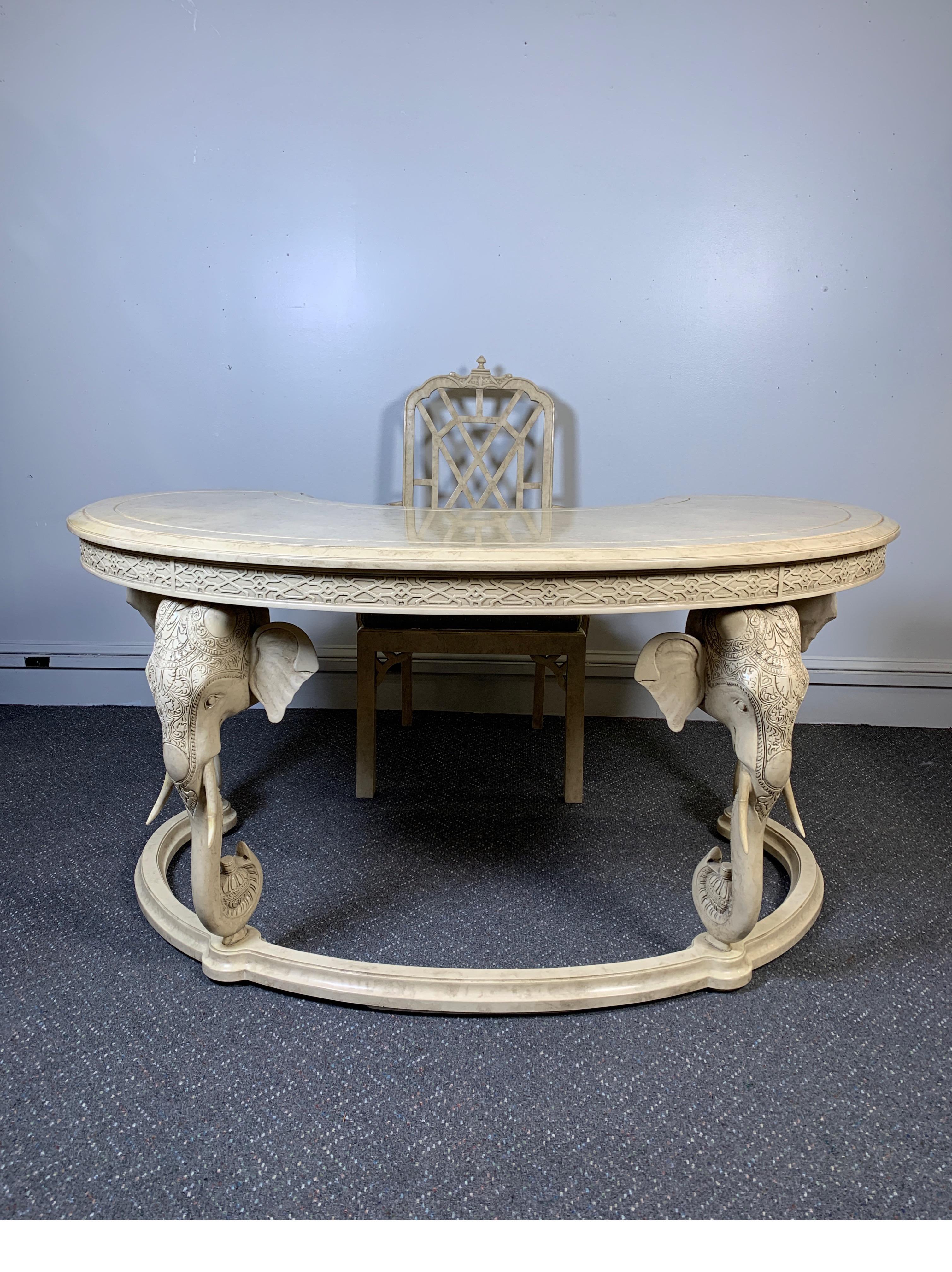 Hollywood Regency kidney desk with chair by Gampel Stoll. The ivory faux painted goatskin lacquered finish on both the desk and matching chair. The kidney shaped desk top with single central drawer with four carved elephant motif legs. The apron