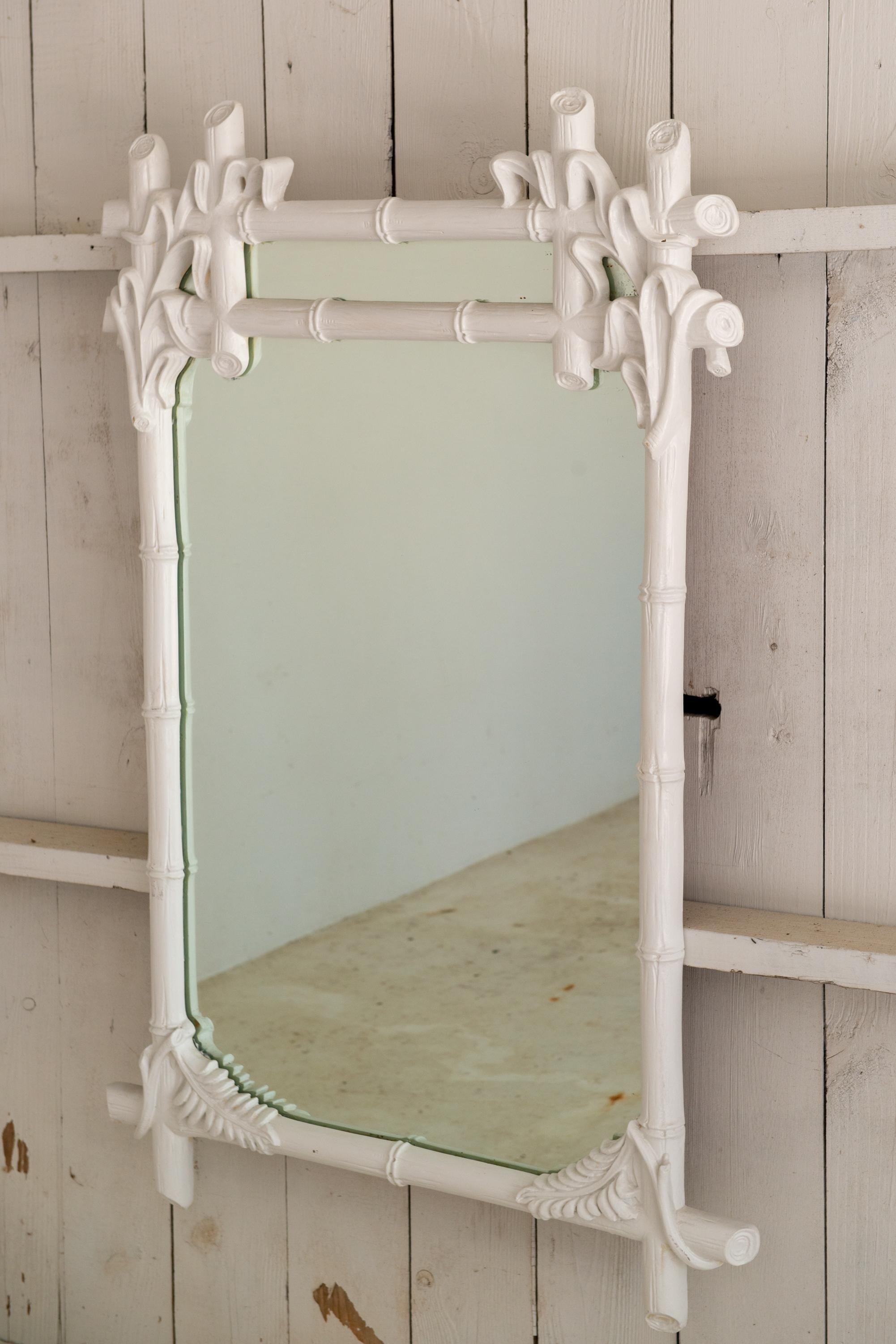 Un grand miroir en bois sculpté peint en blanc de Gampel-Stoll, typique du style Hollywood Regency. Ce miroir de style Chinoiserie du milieu du 20ème siècle est sculpté de façon complexe dans un style bambou et feuillage. Il s'agissait d'un morceau