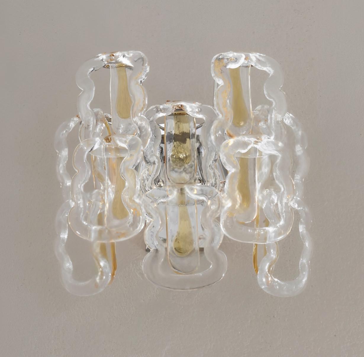 Aplique italiano con ganchos de cristal de Murano transparente decorado con rayas de color ámbar en el centro, montado sobre un marco de metal cromado / Fabricado en Italia
2 luces / tipo E12 o E14 / máx. 40W cada una
Medidas: ancho 14 pulgadas /