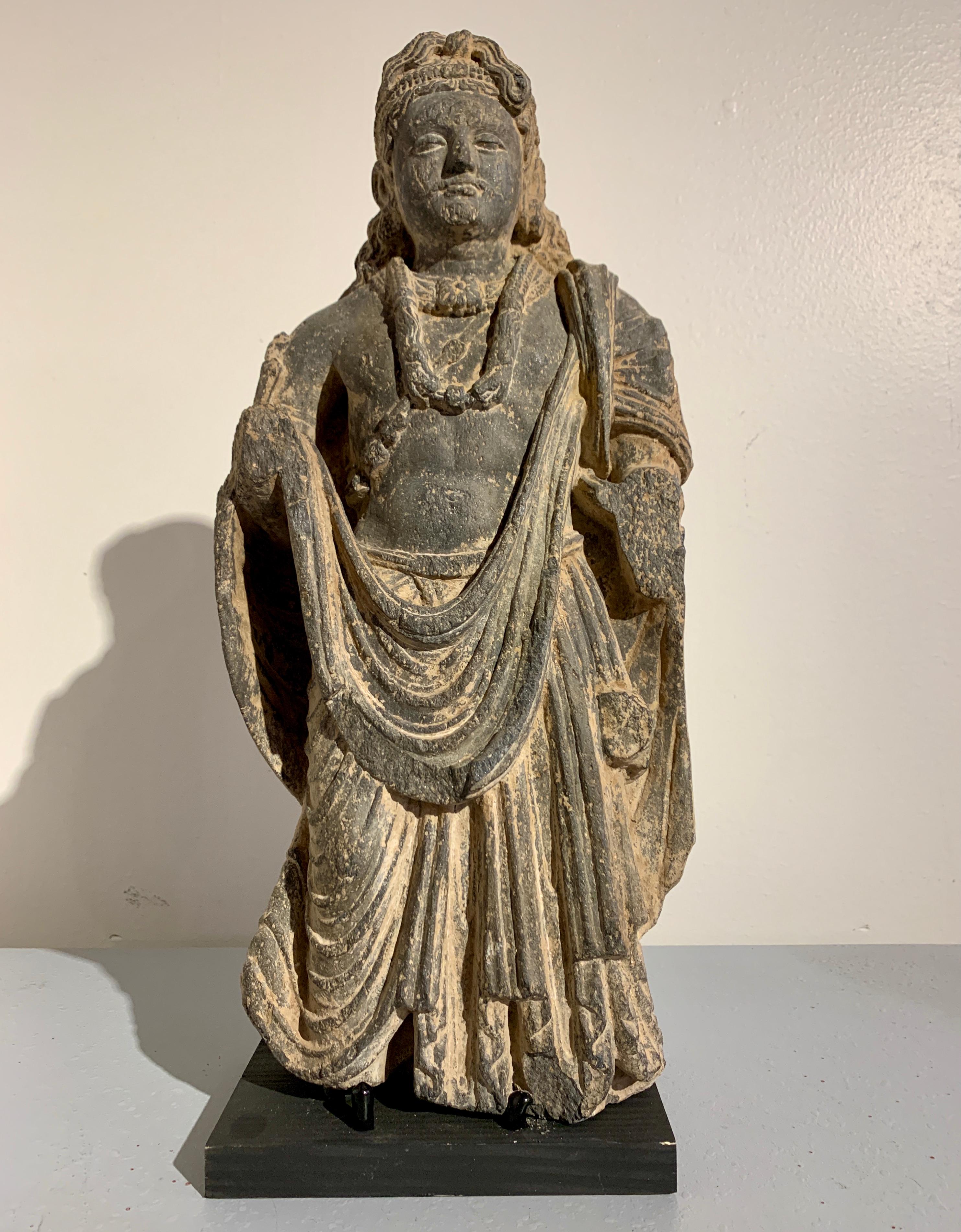 An impressive and well carved Gandharan figure of the Bodhisattva Maitreya, the Buddha of the Future, carved black schist, ancient Kingdom of Gandhara, 2nd-4th century.

Maitreya is portrayed standing upright, one knee slightly bent in