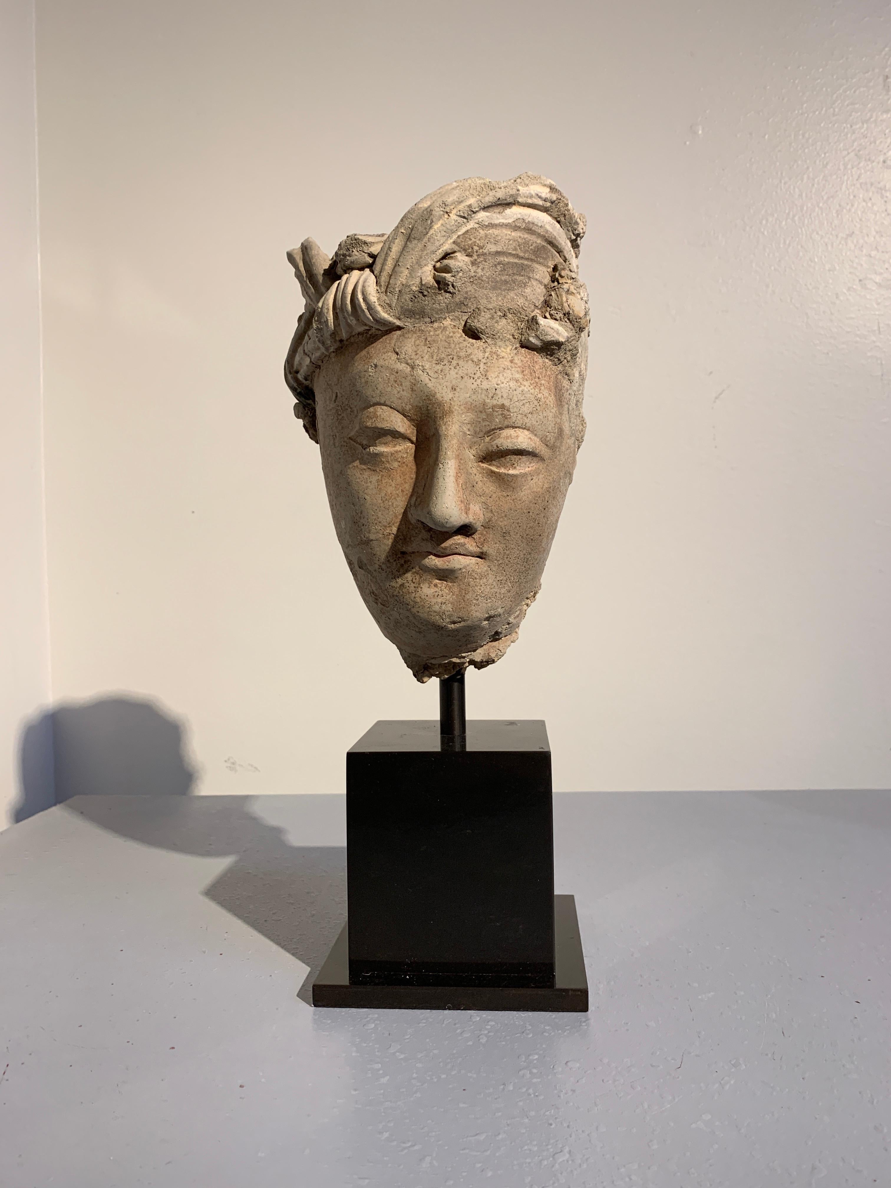 A striking Gandharan molded stucco head of a male Bodhisattva, tentatively identified as Manjushri, ancient region of Gandhara, probably Hadda or surrounding area, 3rd-5th century.

The Bodhisattva is sculpted of stucco in an idealized manner as a