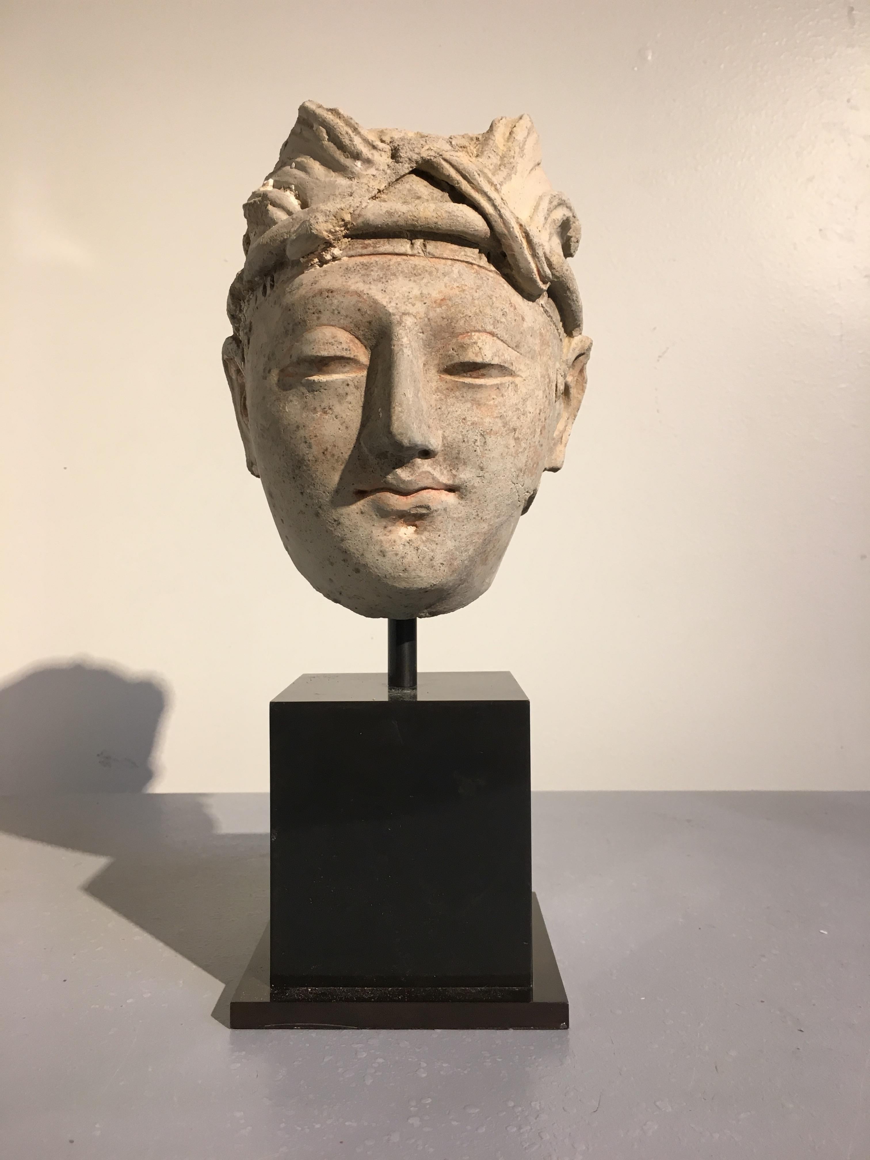 A sublime molded stucco head of a young male donor from the ancient region of Gandhara, 4th-5th century. 

The youthful nobleman sculpted in an idealized manner, with soft and kind features, a benign expression on his face. He wears a pleated