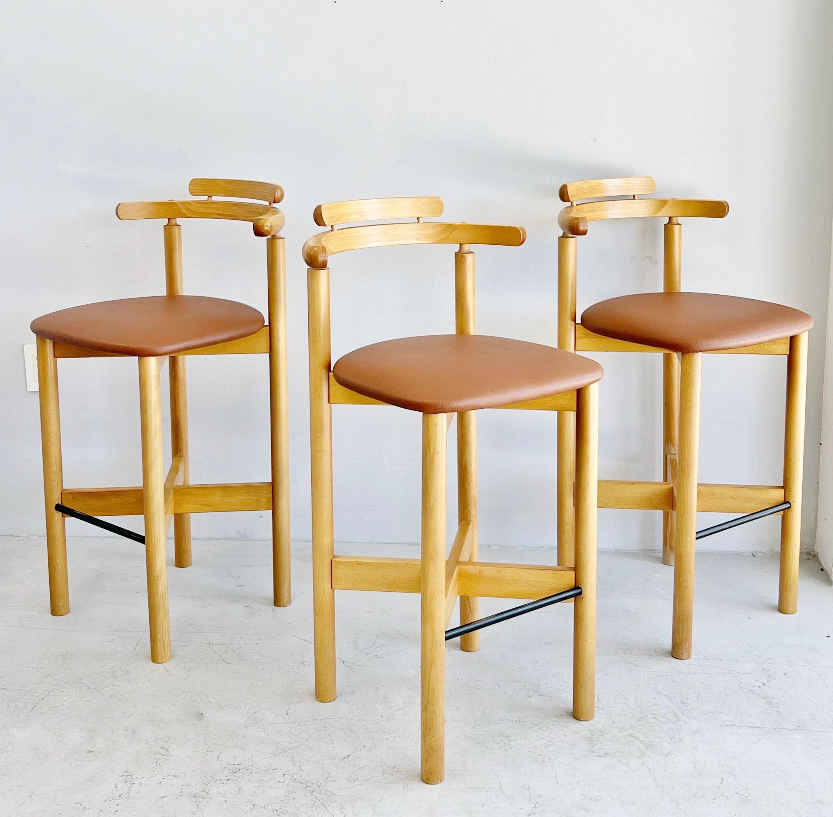 A set of modern barstools by Gangso Mobler. Done in solid wood and upholstered seats with black metal foot rests.