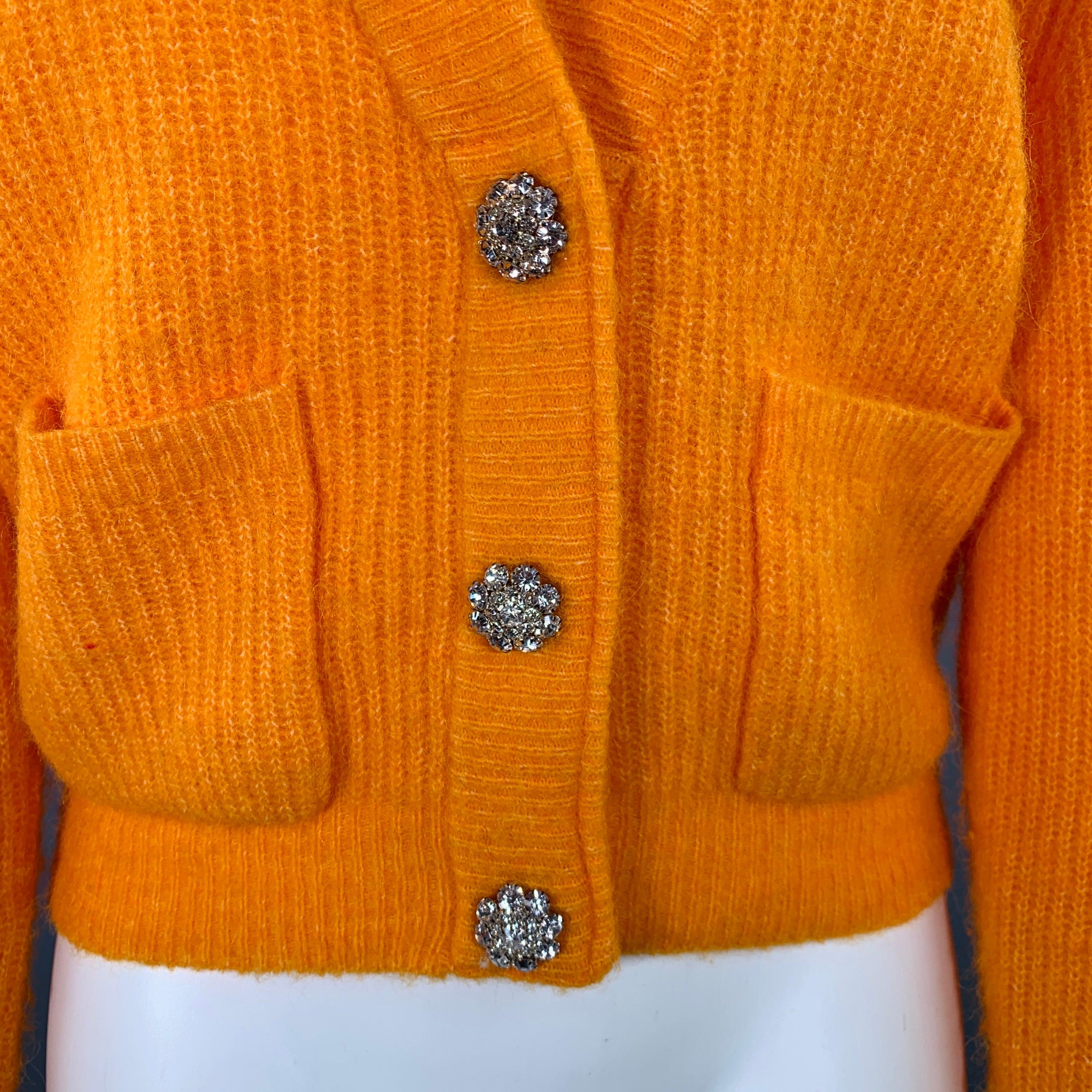 GANNI cardigan
in an orange alpaca blend knit featuring two pockets, V-neck, and rhinestone snap closure.Very Good Pre-Owned Condition. Some pilling. 

Marked:   S 

Measurements: 
 
Shoulder: 17 inches  Bust: 40 inches  Sleeve: 25.5 inches Length: