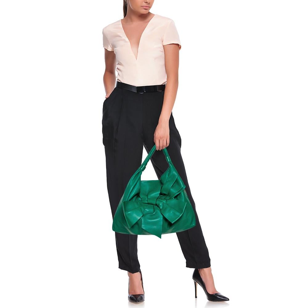 This Valentino green-hued hobo has a Nappa leather exterior and an oversized bow on the front. Its large slouchy structure makes it perfect to house all your essentials with ease. The hobo has twin handles and a satin-lined interior featuring a zip