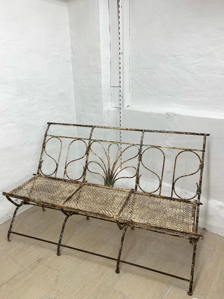 Antique French garden bench in wrought iron with great patina. The back has a very neatly shaped pattern and has a light feel to it. Decorative and useful indoors as well as outdoors.