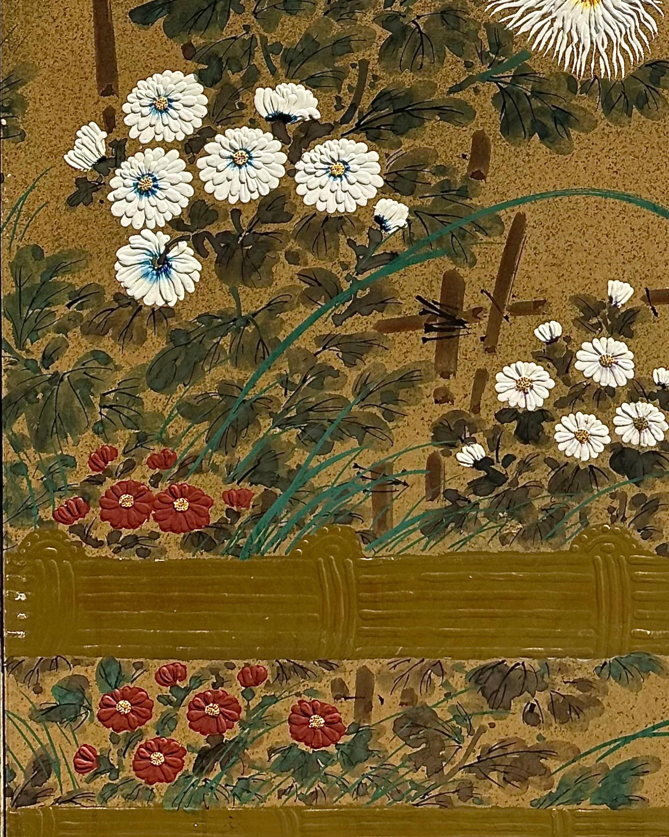 Vor einem schimmernden goldenen Hintergrund blühen Chrysanthemen in Weiß, Karminrot und Gelb - Blumen, die in der japanischen Kultur Langlebigkeit, Adel und den ewigen Kreislauf des Lebens symbolisieren. Gestützt von Bambuspfählen und umrahmt von