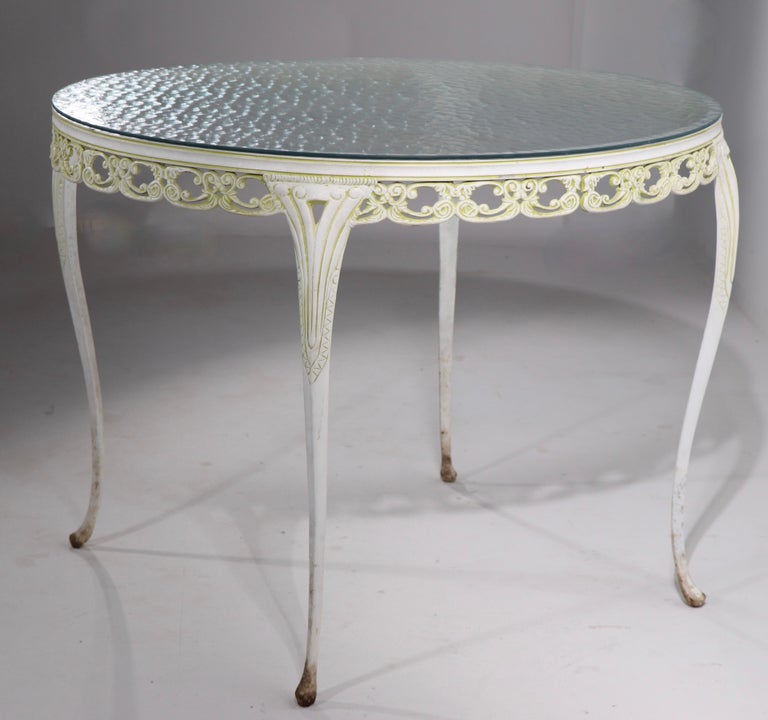 Elegant and charming diminutive cafe dining table. This example has a cast aluminum base with foliate trim and cabriole legs, the top is the original textured plate glass. No structural damage, cosmetic wear to finish, normal and consistent with