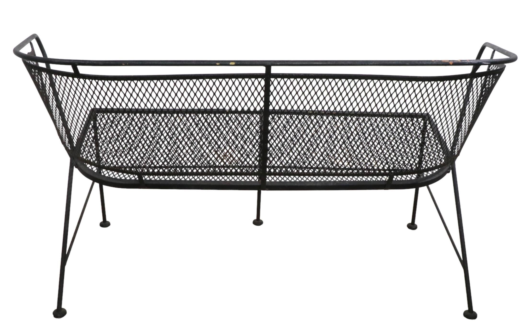 Mid-century wrought iron and metal mesh settee, loveseat, sofa attributed to Salterini. The loveseat features a metal mesh seat and back rest, with wrought iron frame. This example is in very good, original condition, showing only cosmetic wear,