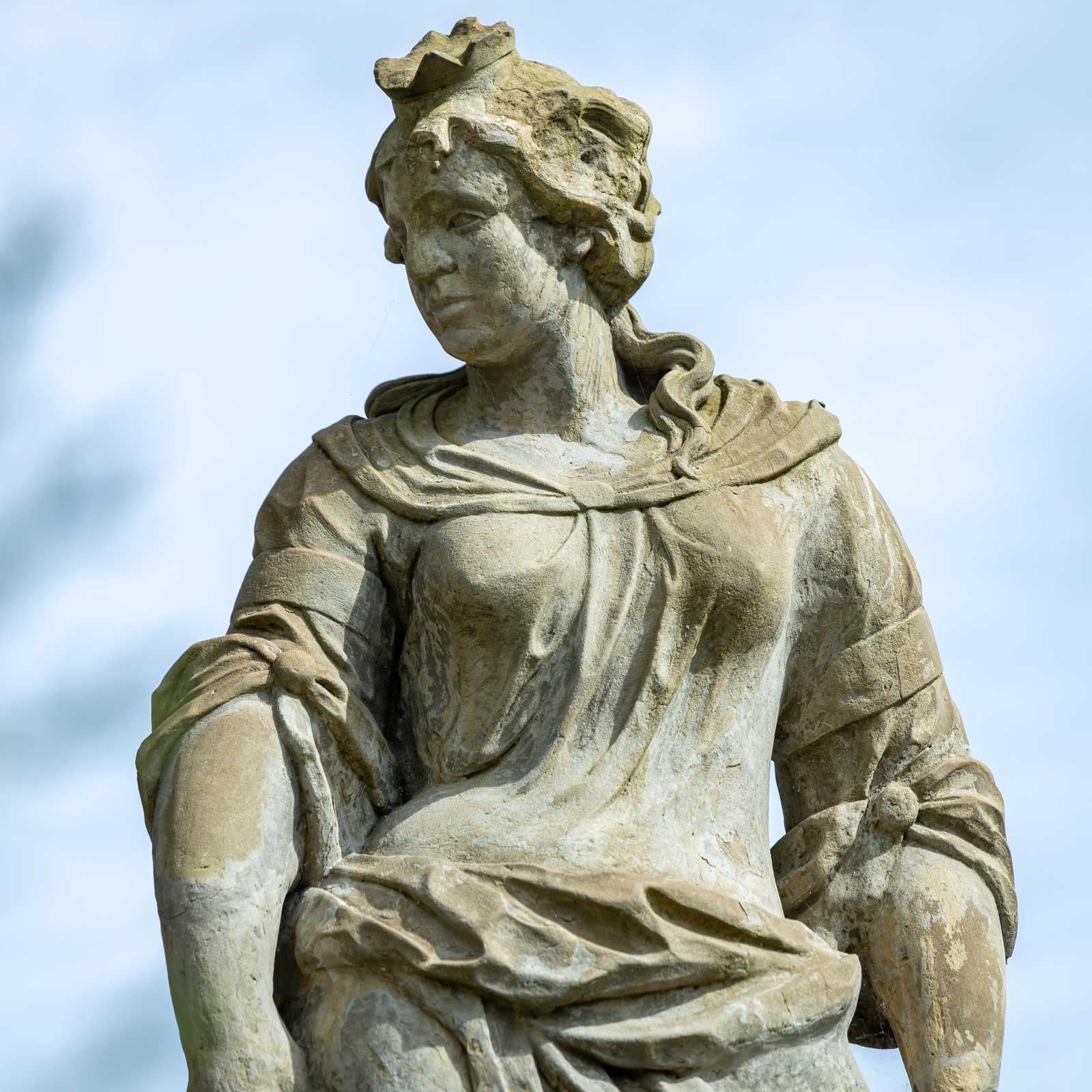 Statua a grandezza naturale della dea Era con corona e il suo attributo del pavone al fianco. La scultura ha una bella patina autentica. La scultura da giardino è realizzata in pietra arenaria. Manca una mano. Nell'altra tiene una falce.  