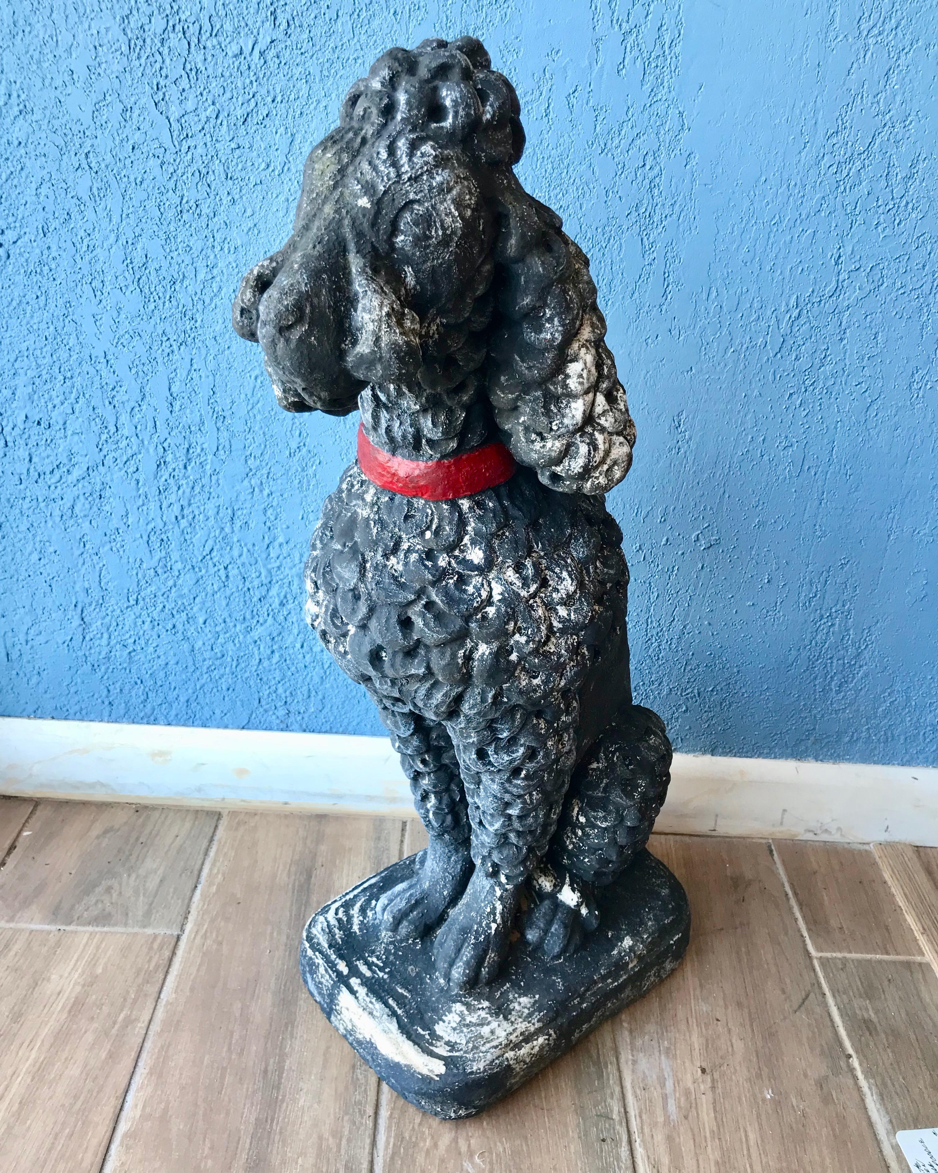 Nicely fashioned in the form of a seated miniature poodle cast in old concrete 
with a wash of black paint.
A fine and worthy garden sculpture.