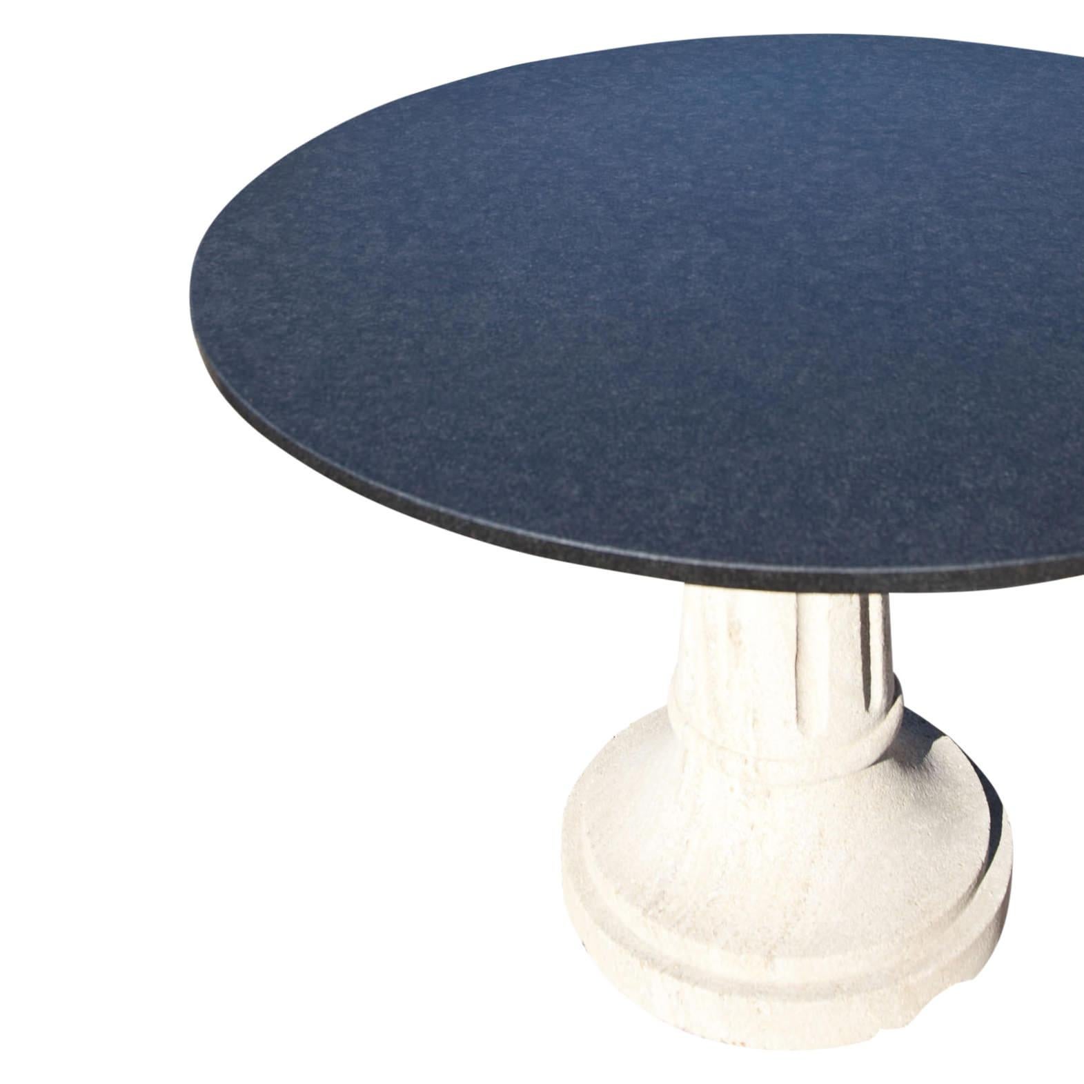 Round garden table with a black granite stone top. The likewise round foot is made of sandstone and fluted.