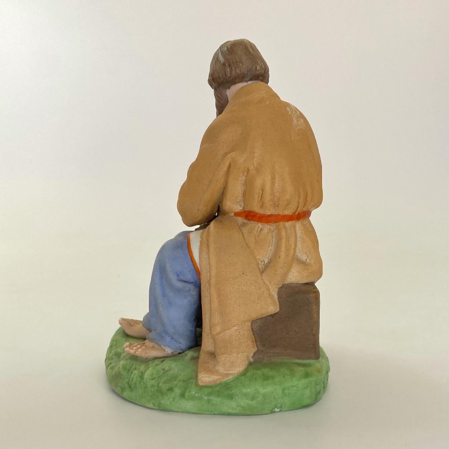 Russian biscuit porcelain figure, Gardner Factory, Moscow, c. 1880. Modelled as a seated peasant, preparing his lunch, by salting his bread. Having a tall hat, and his boots by his side, upon a circular grassy mound.
Printed and impressed factory
