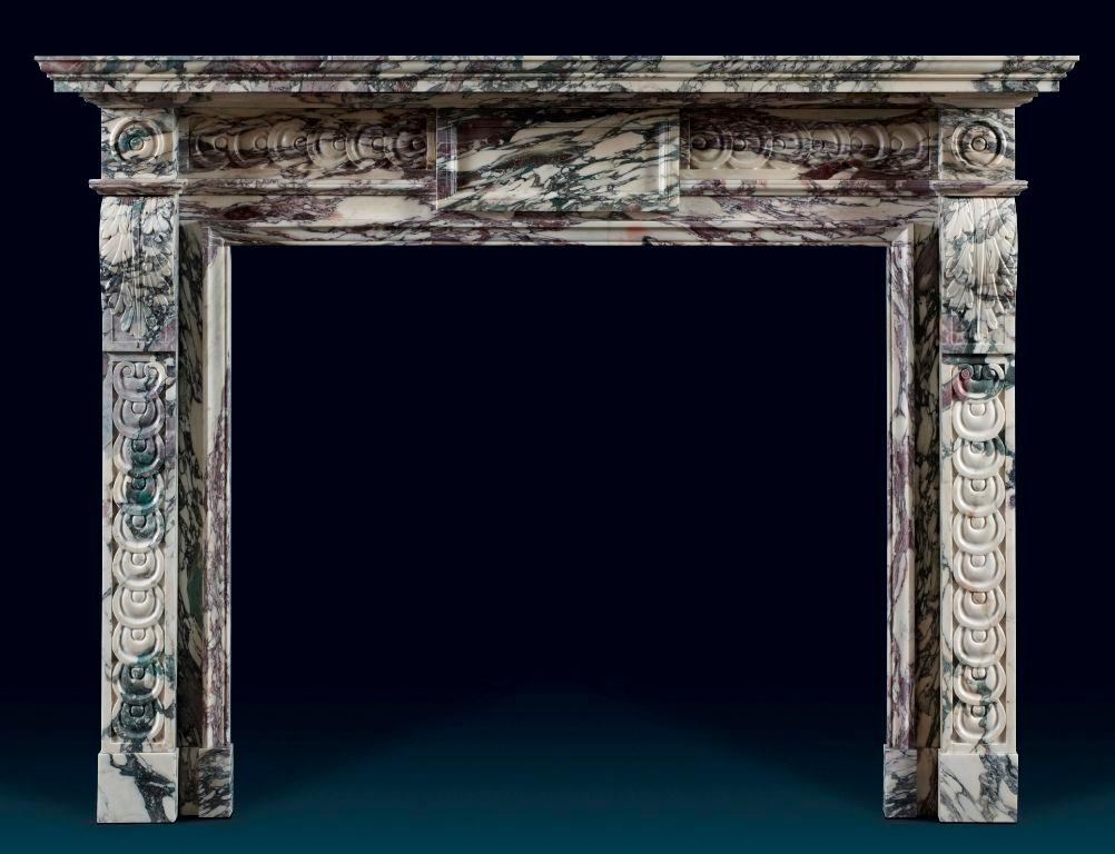 No expense has been spared in producing this beautiful chimneypiece. The shelf and jambs are carved out of solid blocks of breche in the traditional 18th century manner. The corner blocks, decorated with circular paterae, are carved out of one piece