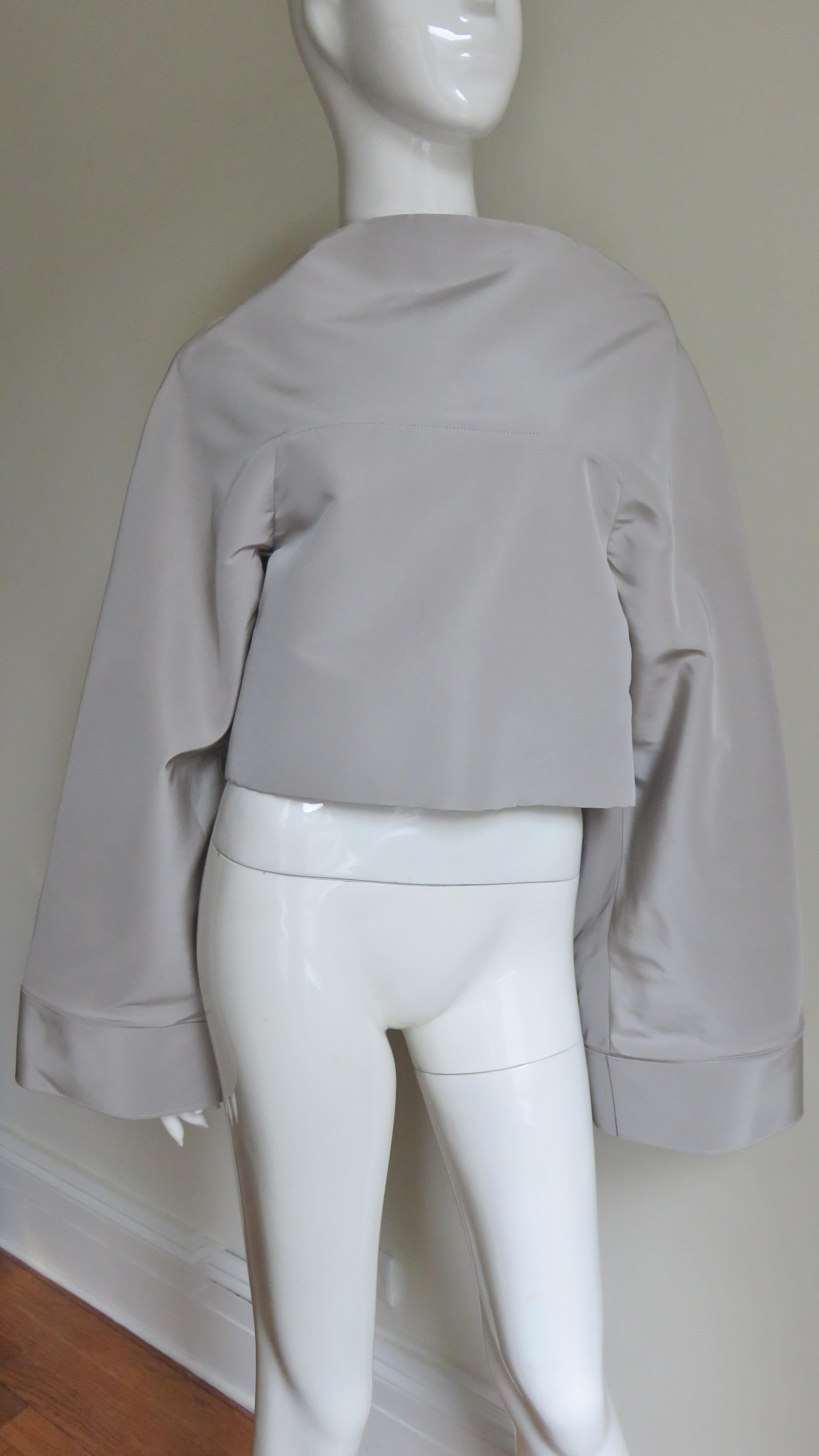 An incredible pale taupe silk jacket top by Gareth Pugh. It has a curved bateau neckline and a front yoke incorporating the wide cuffed sleeves. The back has a separating zipper and the top is lined in the same fabric. 
Fits sizes Extra Small,
