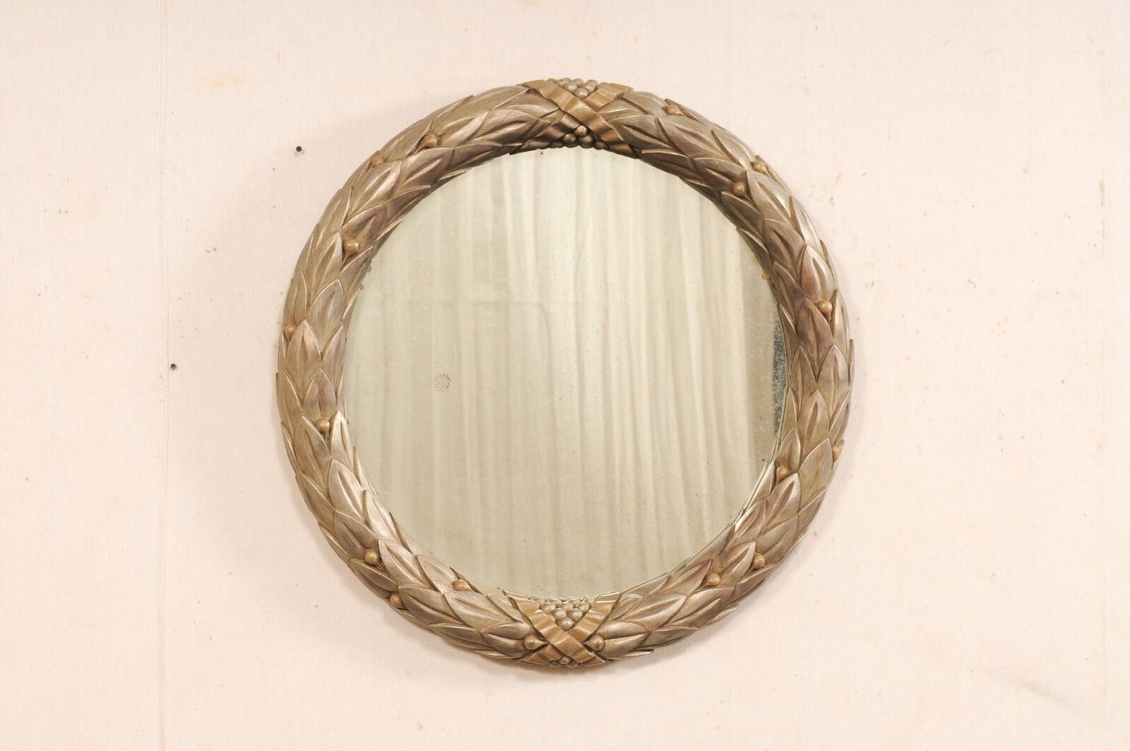 A vintage artisan crafted round mirror with Garland carved-wood motif frame. This hand-carved vintage American circular mirror was beautifully designed with Venetian style influences. It features a carved wood surround, in a garland motif, with