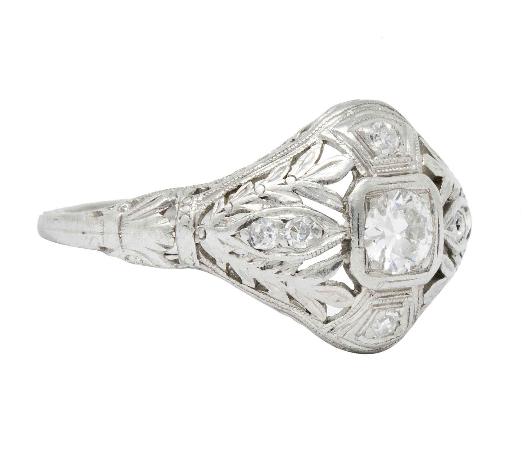 Centering an old European cut diamond weighing approximately 0.20 carat, H color and SI1 clarity

Bead set in a square form sitting low in the pierced foliate mounting with stylized leaf shoulders and engraving partially down shank

Accented at each