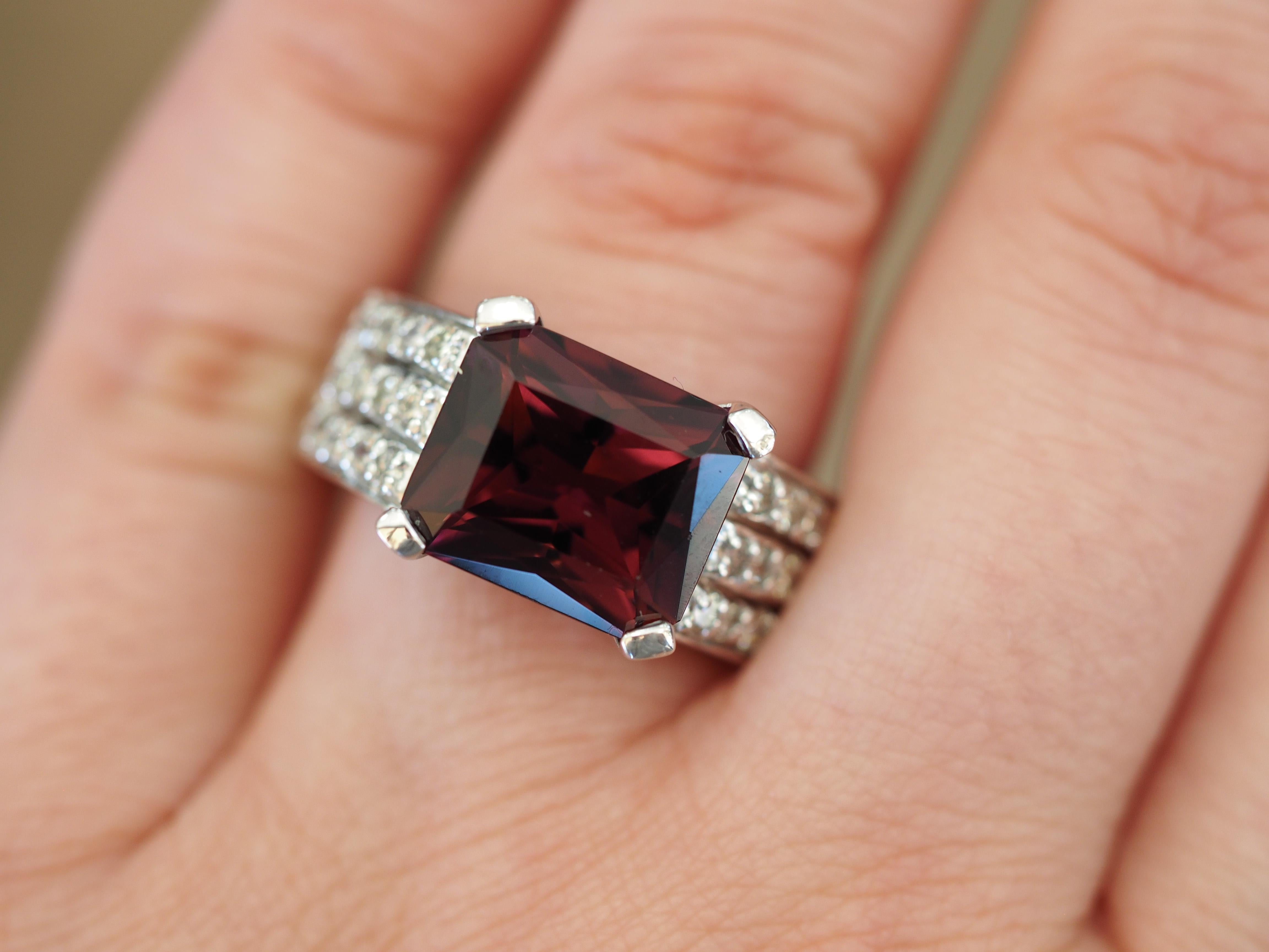 This modern vintage design includes a one of a kind rich emerald cut Garnet. The  Garnet has a deeply desired rich color, the pinkish red color are immediately captivating at first glance. The lavish tanzanite weighs 6.3 Carats and is accented with 