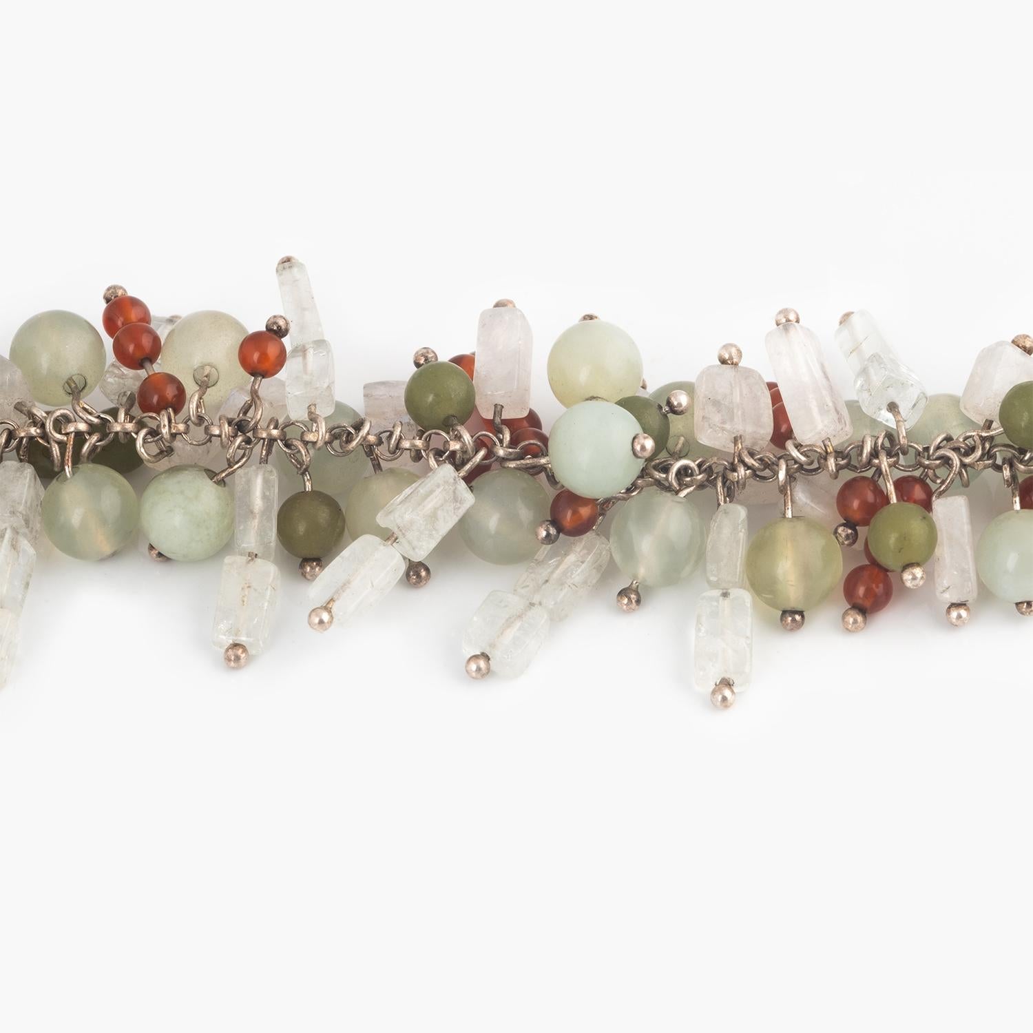Multi hued gemstones including Blue Flash Moonstones, Green Garnet, Carnelian and Apatite are threaded onto sterling silver wire and attached to silver chain with a handmade clasp. 
Gemstone beads are mixed by color, shape, and size for an