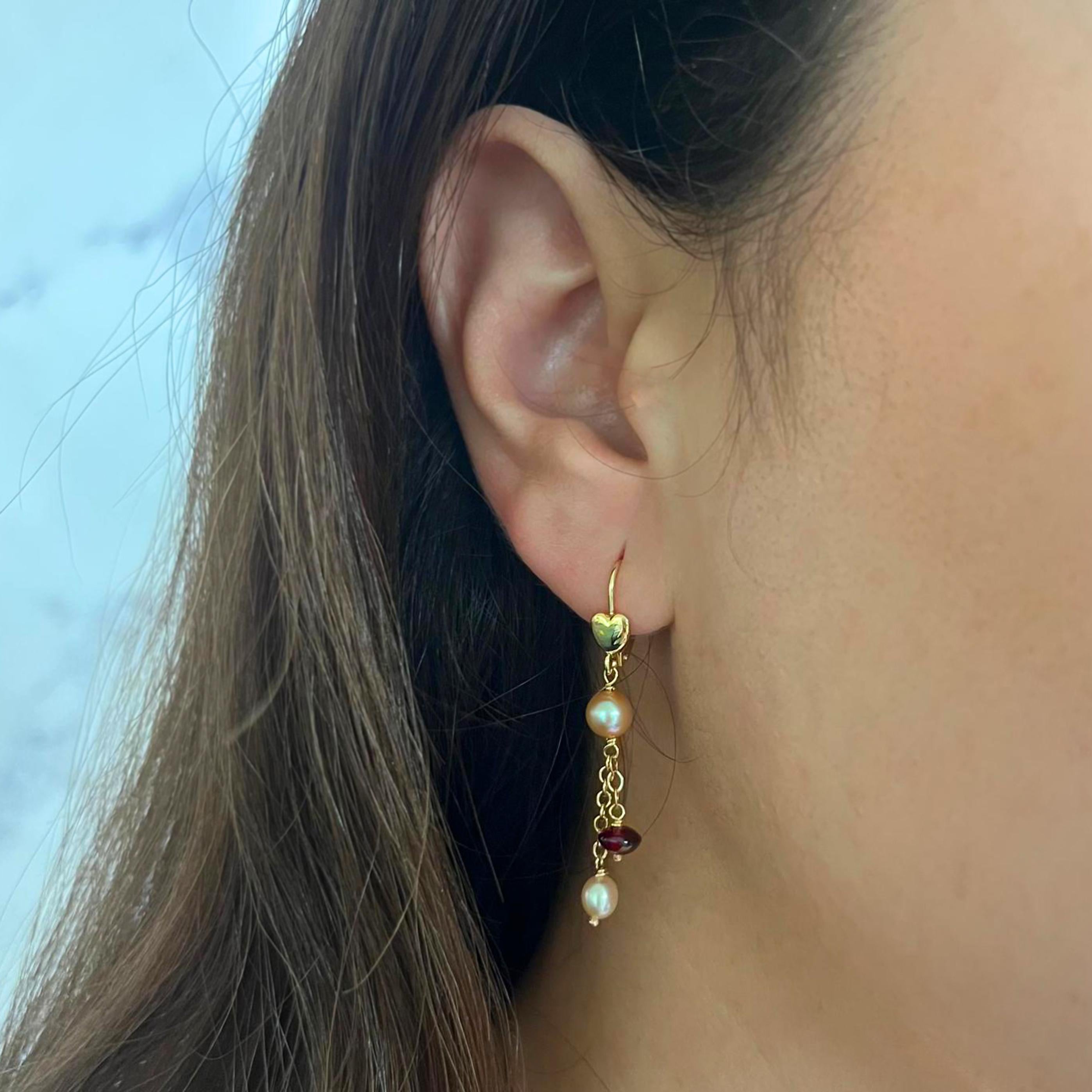 14 karat yellow gold drop earrings featuring 4 pink cultured pearls and 2 garnet beads. 1.75 inch length with French wire back. Finished weight is 2.7 grams.