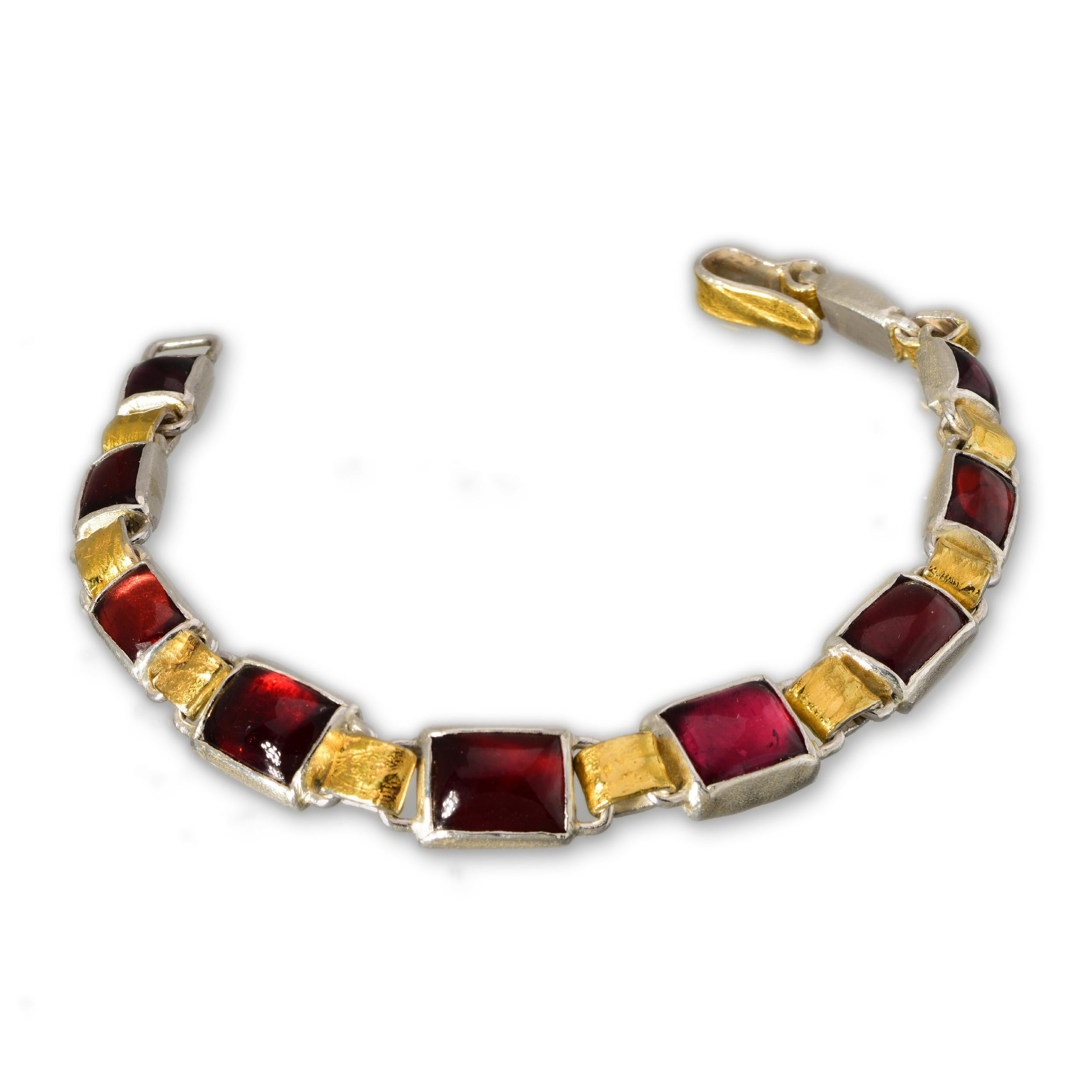 This charming bracelet is made out of deep red wine-coloured garnets and a single secret tourmaline with 22kt yellow gold and silver. The links and the clasp have all been hand-constructed using 22kt gold paper-pressed patterns and textures and