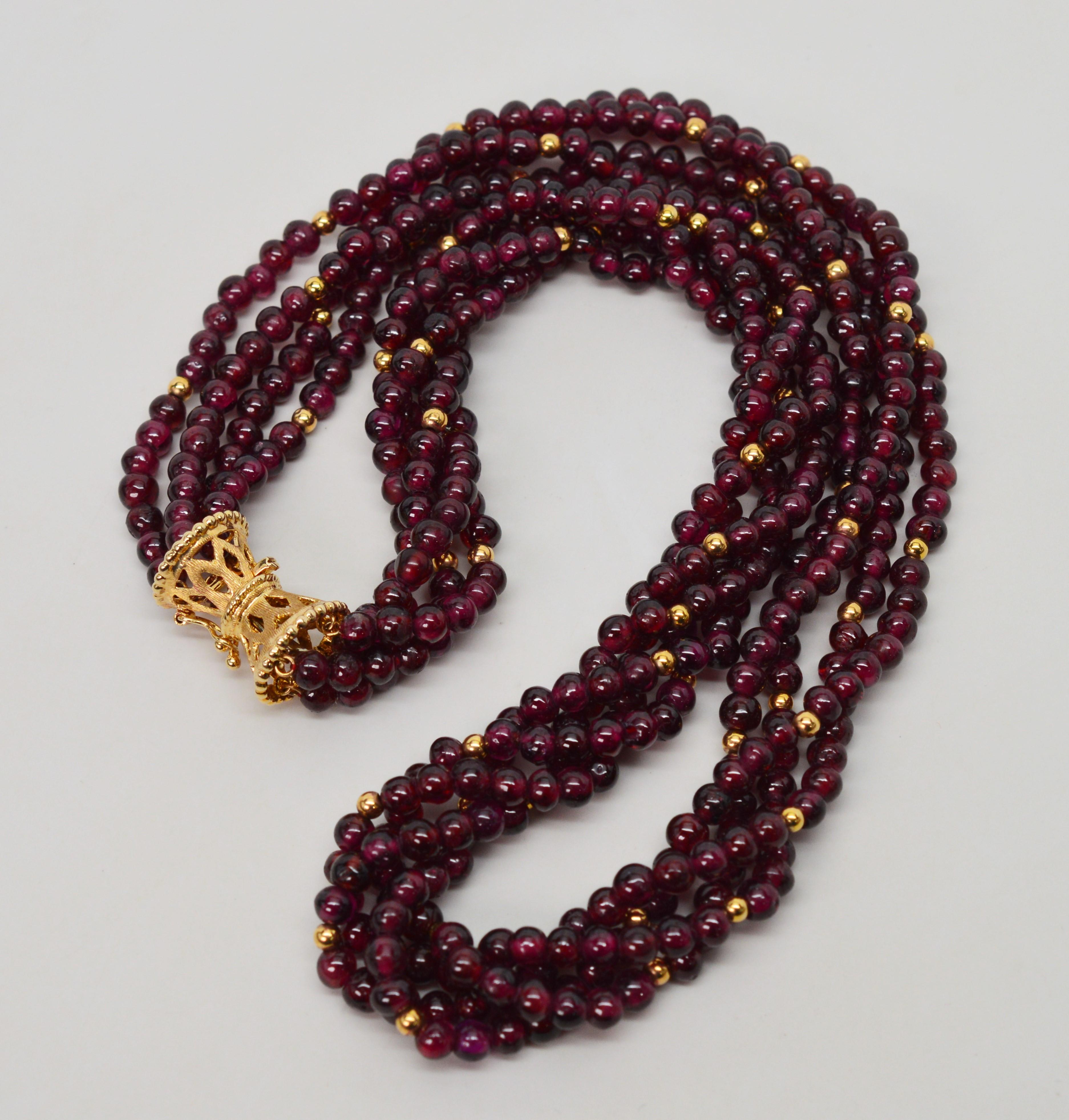 Rich Bordeaux color garnet strands with fourteen carat yellow gold bead accents highlight the natural stone's intensity on this beautiful twenty four inch necklace.  A elegant brushed yellow gold filigree clasp doubles as an ornament for the piece