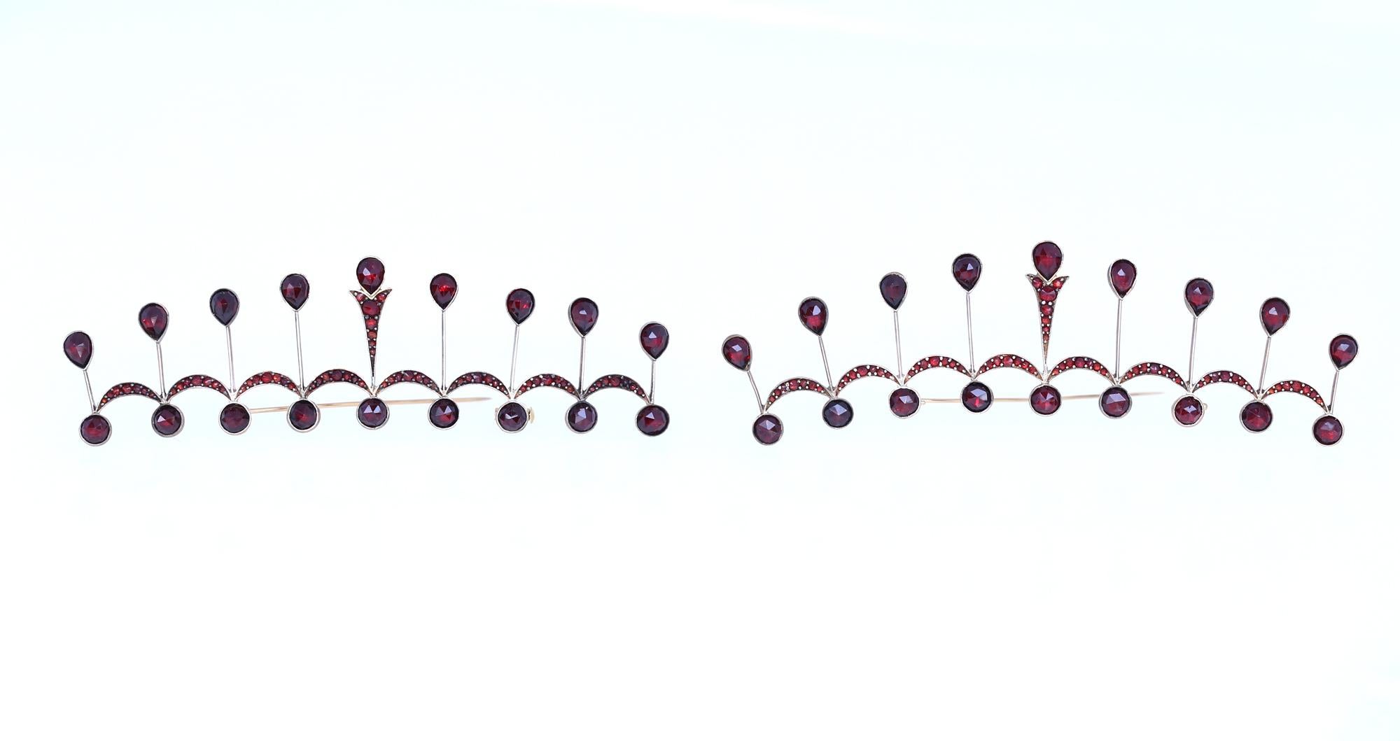 A pair of Garnet Brooches depicting tiara or a crown. Silver with Gold, a technique used at that time. Very unusual and collectable jewelry from the early 20th century. 
Garnet is known to be a stone of the month of January. Very deep red color. It