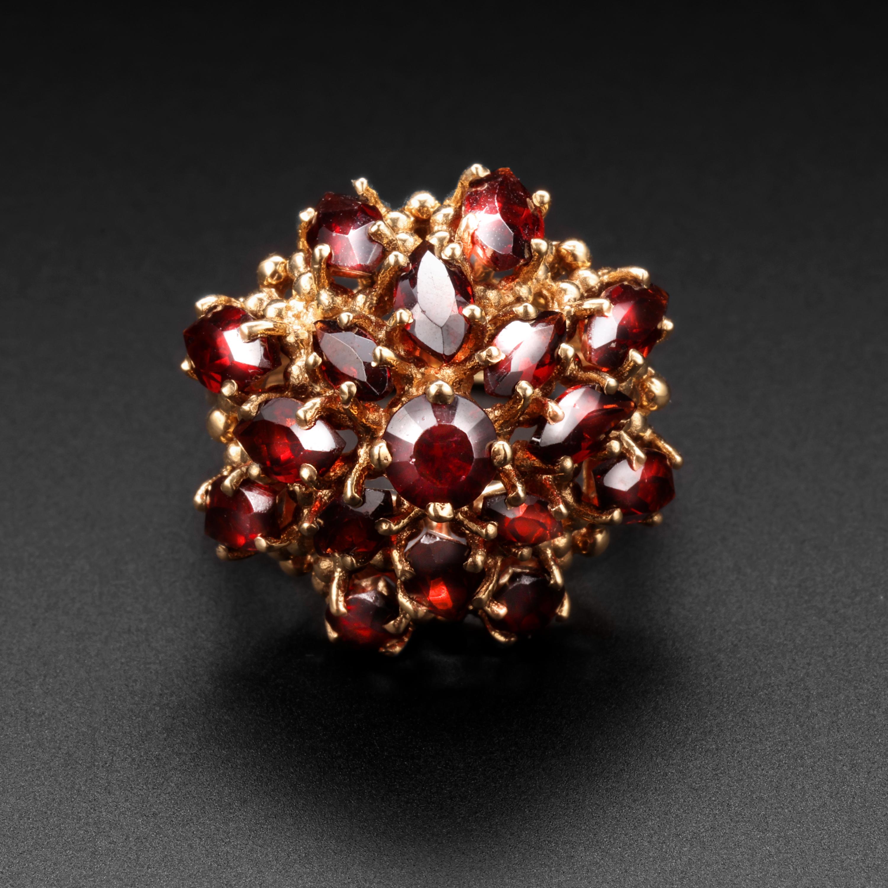 This Mid-Century tower of gold and garnets is the quintessential cocktail ring. 

Hand-crafted from 14k yellow gold between 1955 -1965, this spectacularly cool eye-kidnapping ring is composed of sixteen warm cinnamon-colored marquise-cut and one
