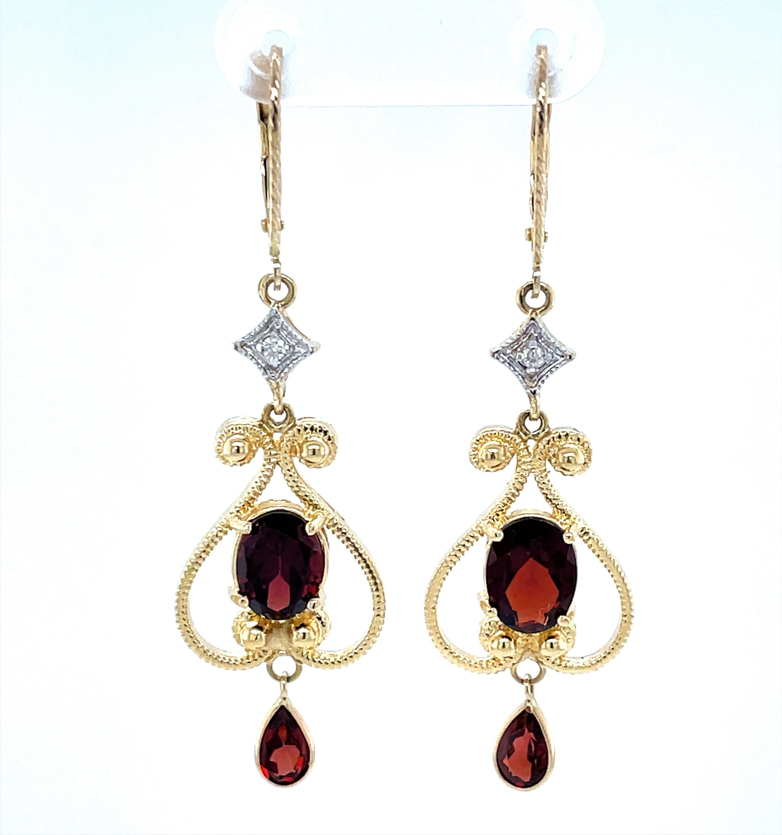 Lovely 14 karat yellow gold earring pair designed in Victorian style with a flowing open scroll motif. Warm 6mm x 8mm oval faceted garnets are the featured stone on each along with a dangle tear drop  3.0 carat TW. Petite round faceted diamond