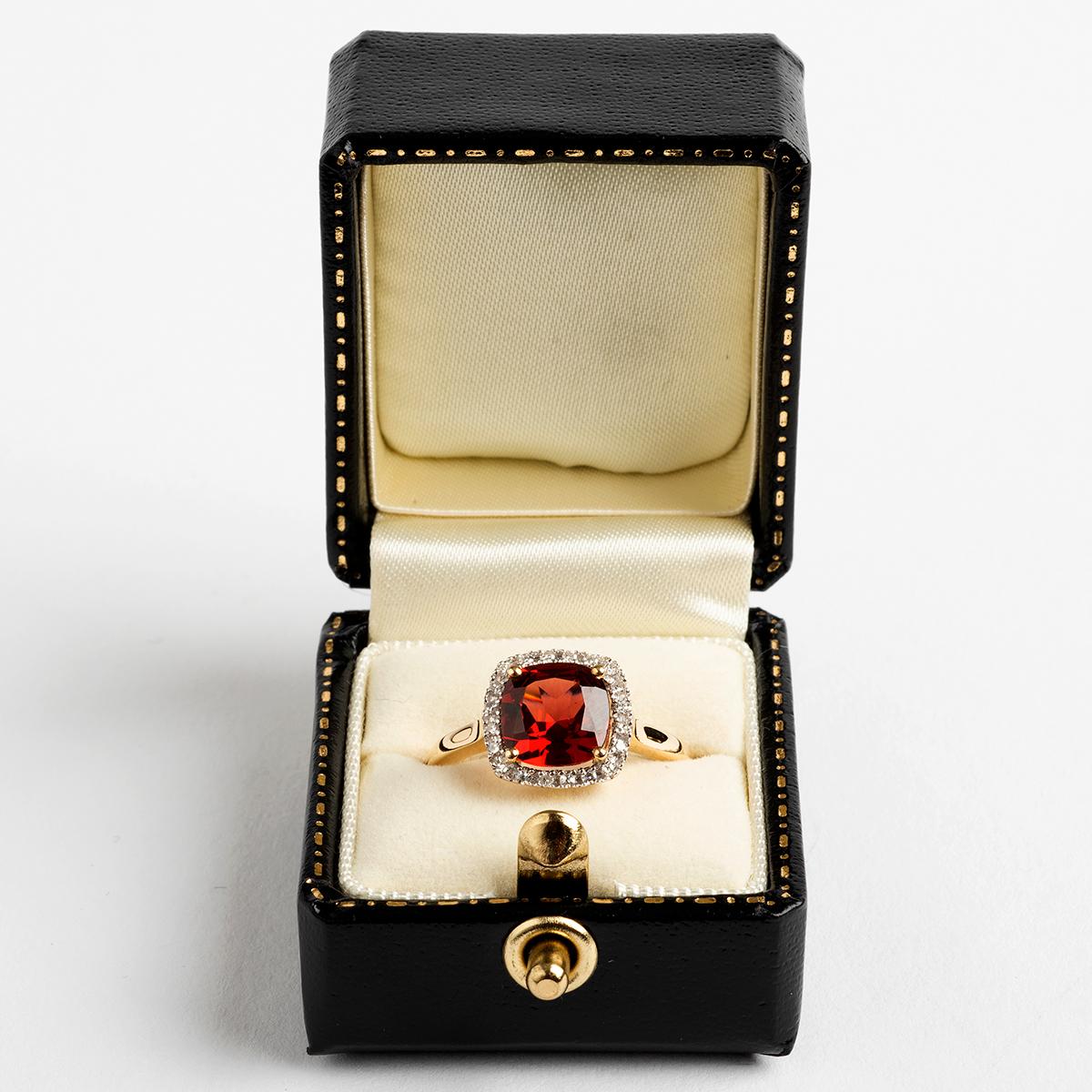 
Our very attractive cluster ring features a large cushion cut garnet (est. 2.05carat) surrounded by brilliant cut diamonds (est. .09carat). The band is 9k yellow gold and is size N. A statement piece in every sense.

A unique piece within our
