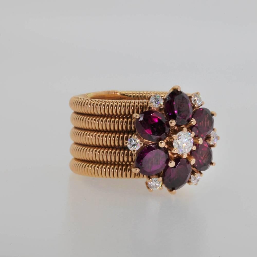 A whimsical, one of a kind Garnet & Diamond ring.  This 1970's 18KT rose gold ring designed  with five spring- like bands showing off a large six petal Garnet flower.   The 4.50 carat Garnet flower centers 0.30 carat Round Brilliant Cut Diamond, and