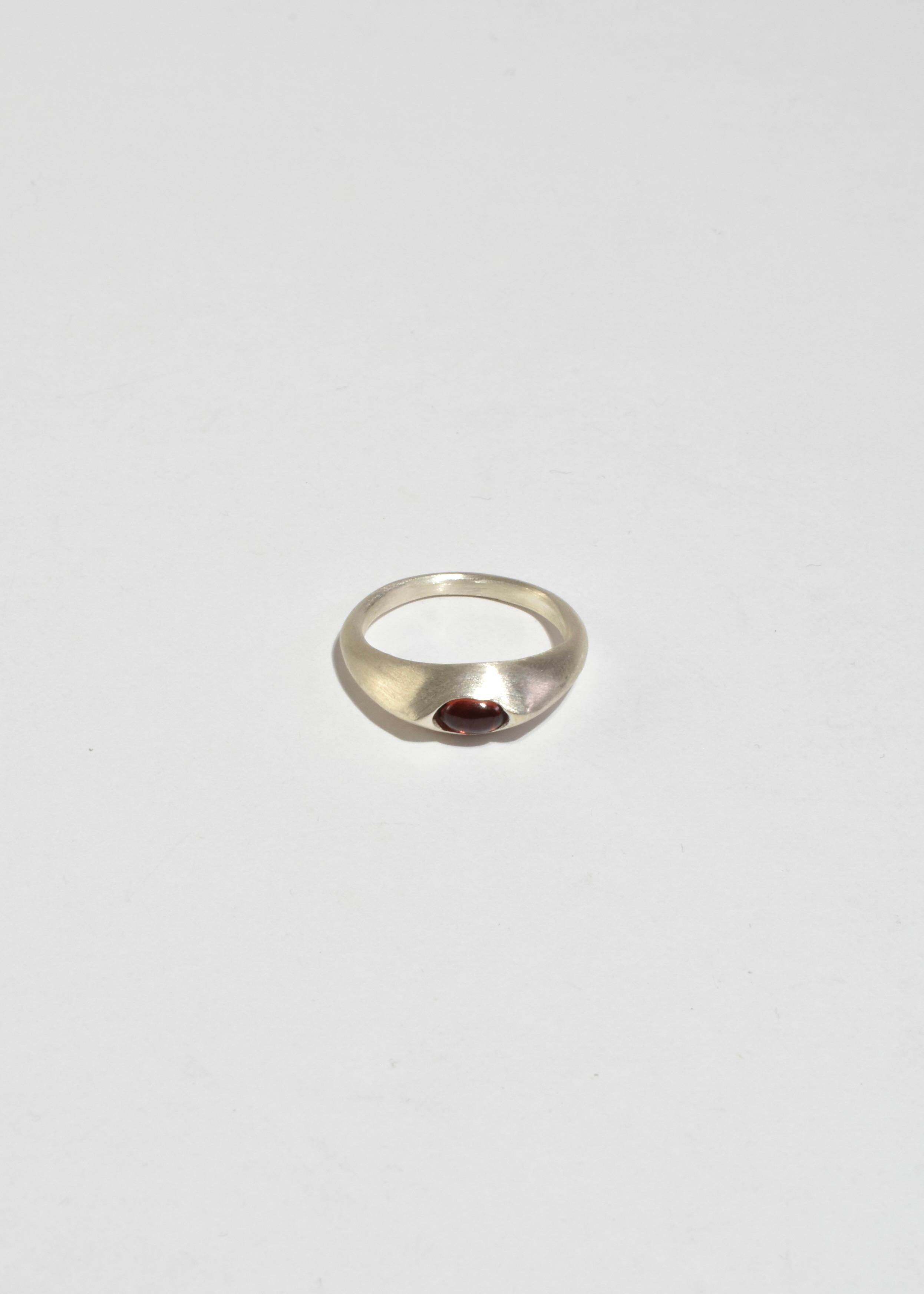 Sterling ring with a garnet cabochon set in an eye-like bezel.

Each piece is hand carved, cast, and finished in New York by Owen Dunton of Dunton Ellerkamp.