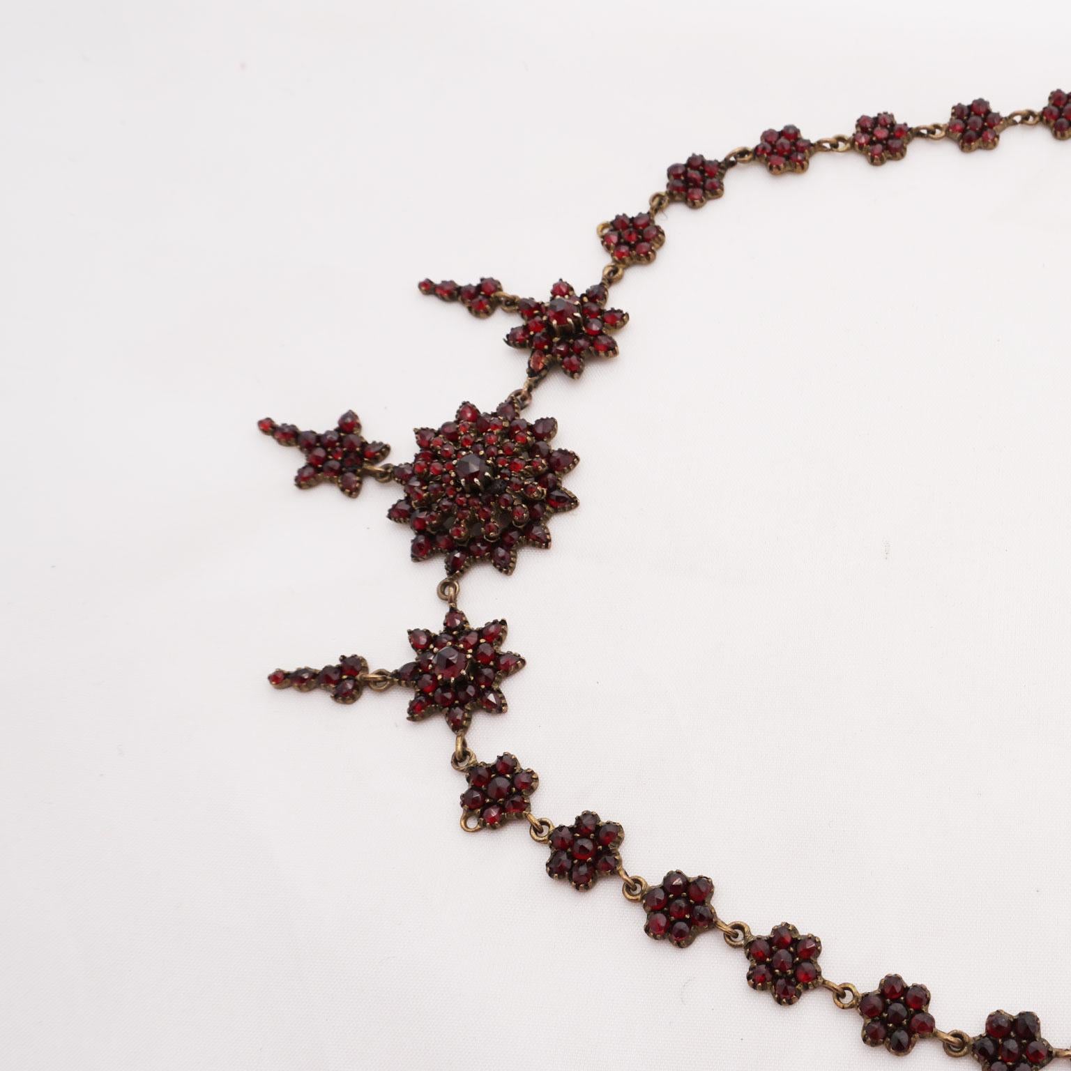 Garnet necklace around 1800
Sumptuous necklace from the time of classicism, worked in tombak, set with Bohemian garnet stones all around. The necklace is made of 26 small star links, each with five garnets. On the front side this necklace shows 3