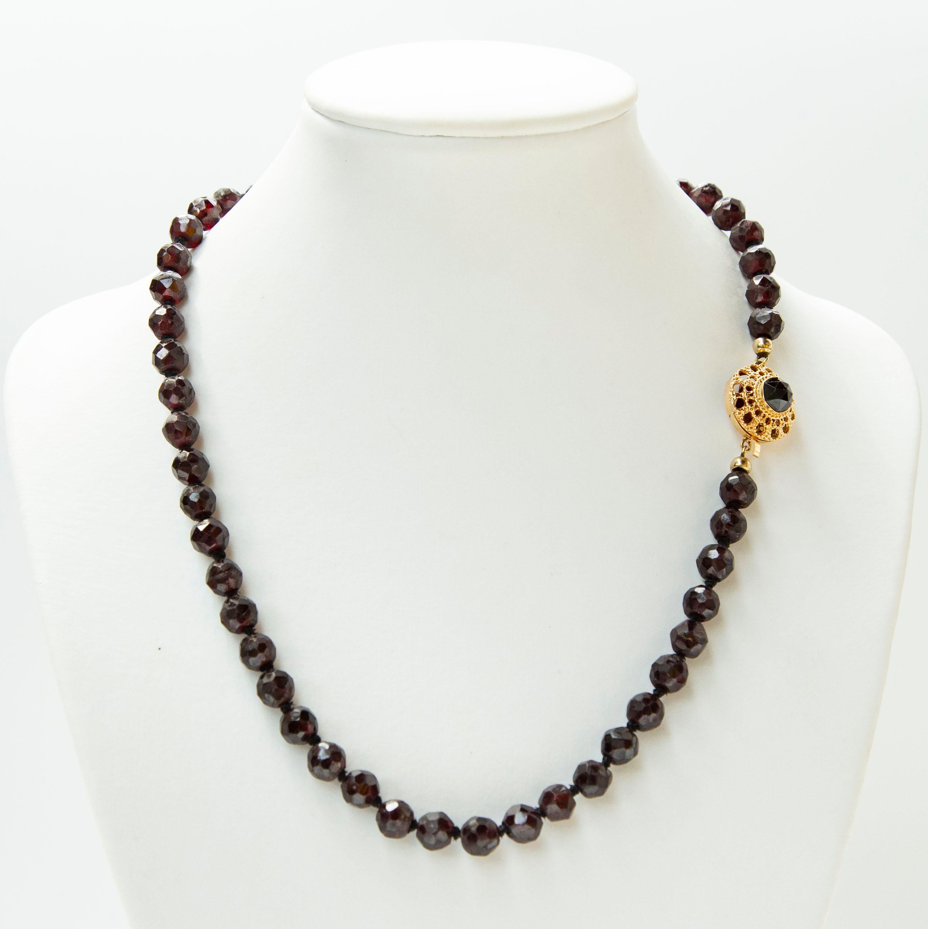 Collana vintage (anni '50 circa) composta da perle di granato sfaccettate e chiusura in filigrana d'oro giallo 14 carati. Le perline hanno un colore viola scuro e profondo e una bella lucentezza. Il diametro delle perle di granato è di circa 8 mm e